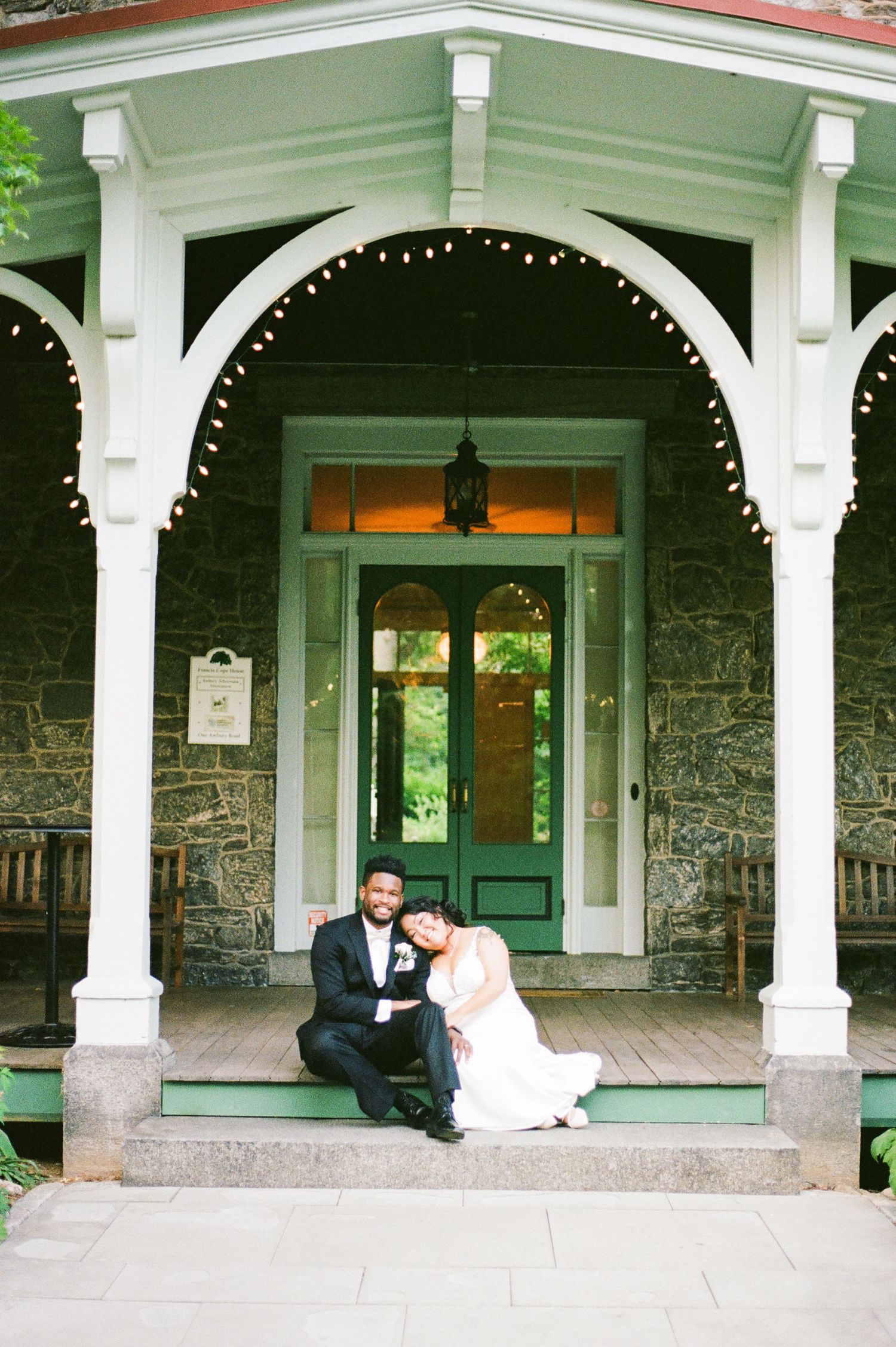 Elegant wedding portraits on vintage porch with white columns and green door.