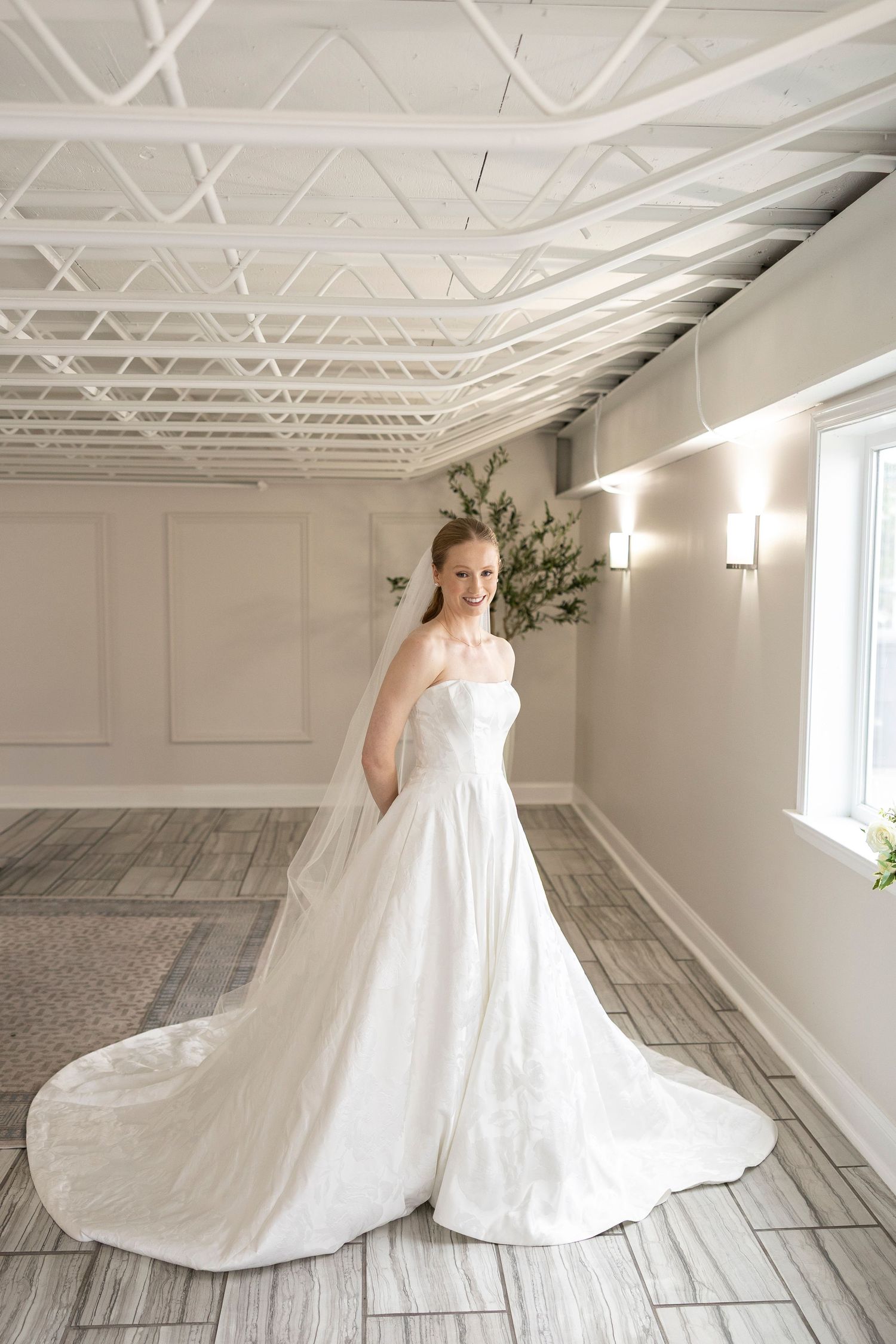 Sweeping wedding dress train creates dramatic silhouette against industrial studio setting.