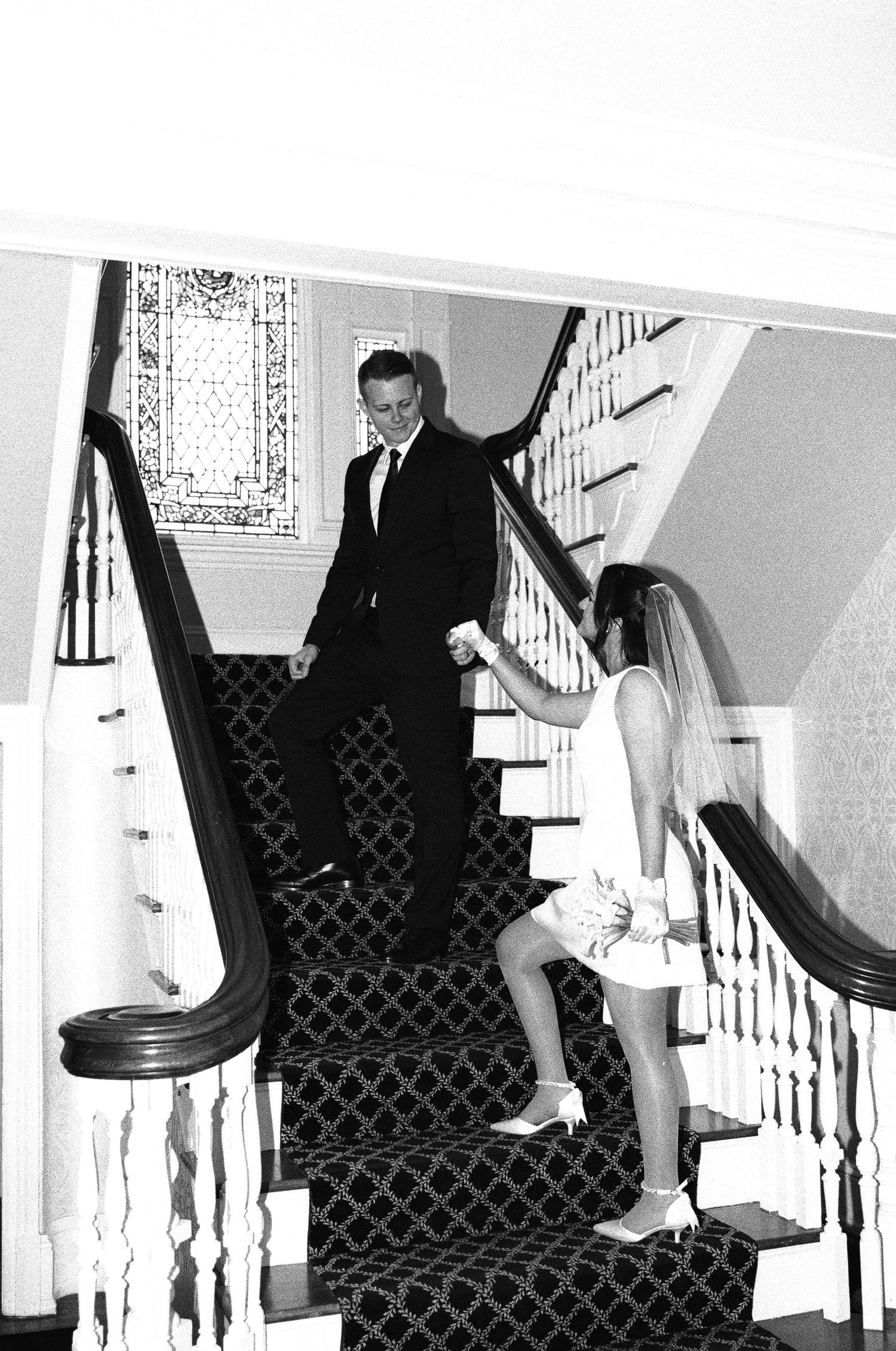 Sequence showing bride and groom playfully sliding down ornate staircase railing at wedding venue.