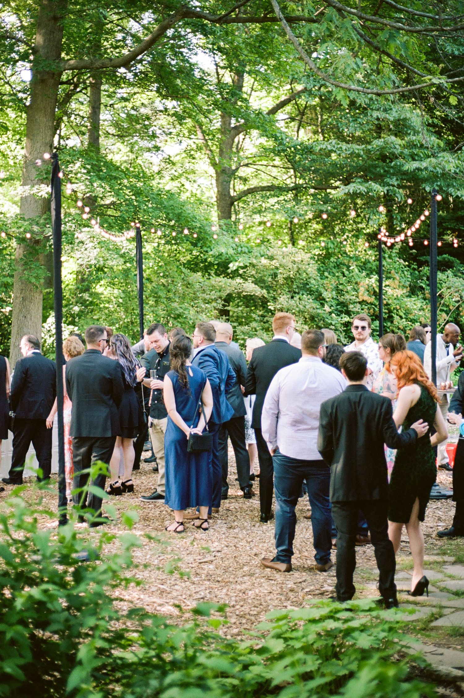 Wedding guests gathered in a wooded outdoor setting for the ceremony.