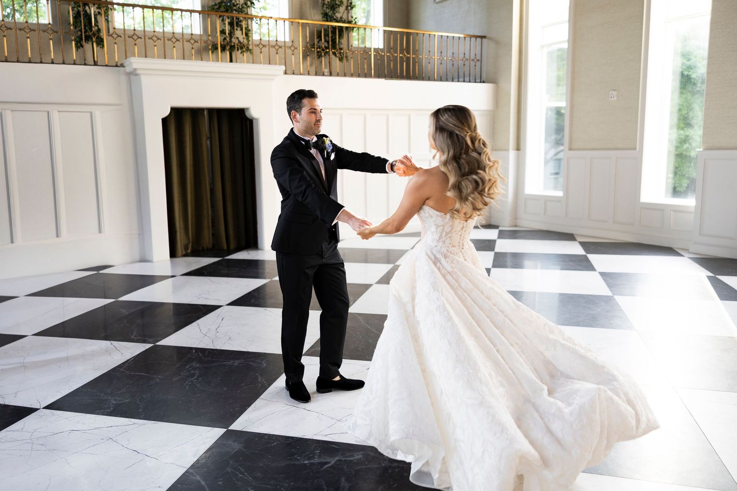 Couple dancing on black and white checkered floor in elegant ballroom.