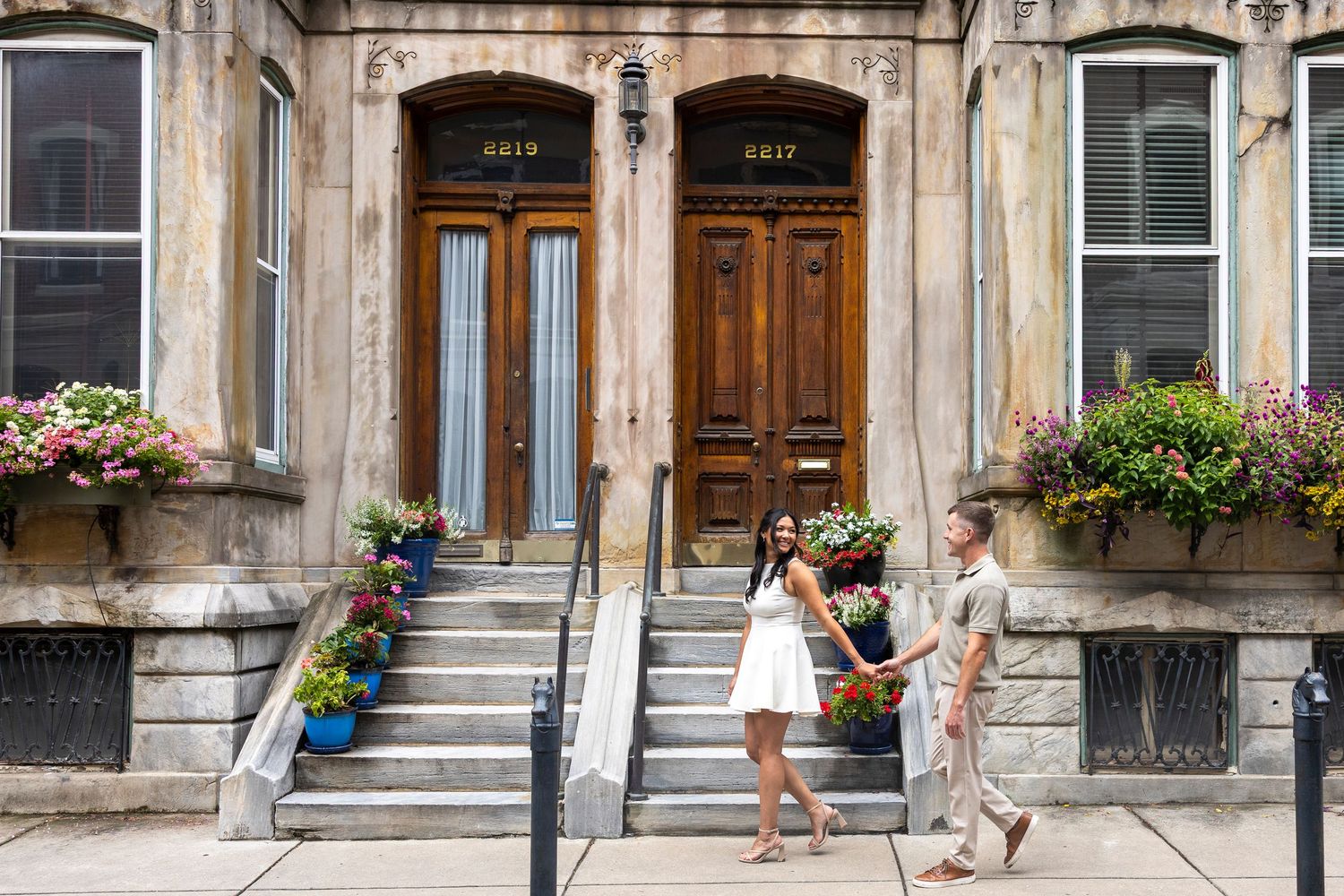 Couple posing playfully in front of classic stone architecture during engagement photoshoot.
