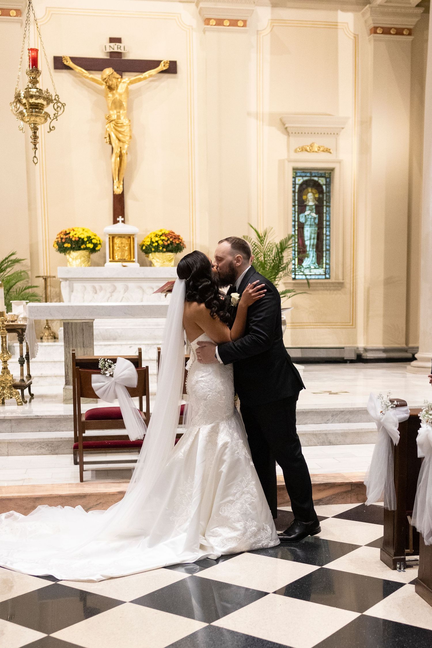 A wedding couple shares their first kiss in a beautiful church with black and white marble floors.