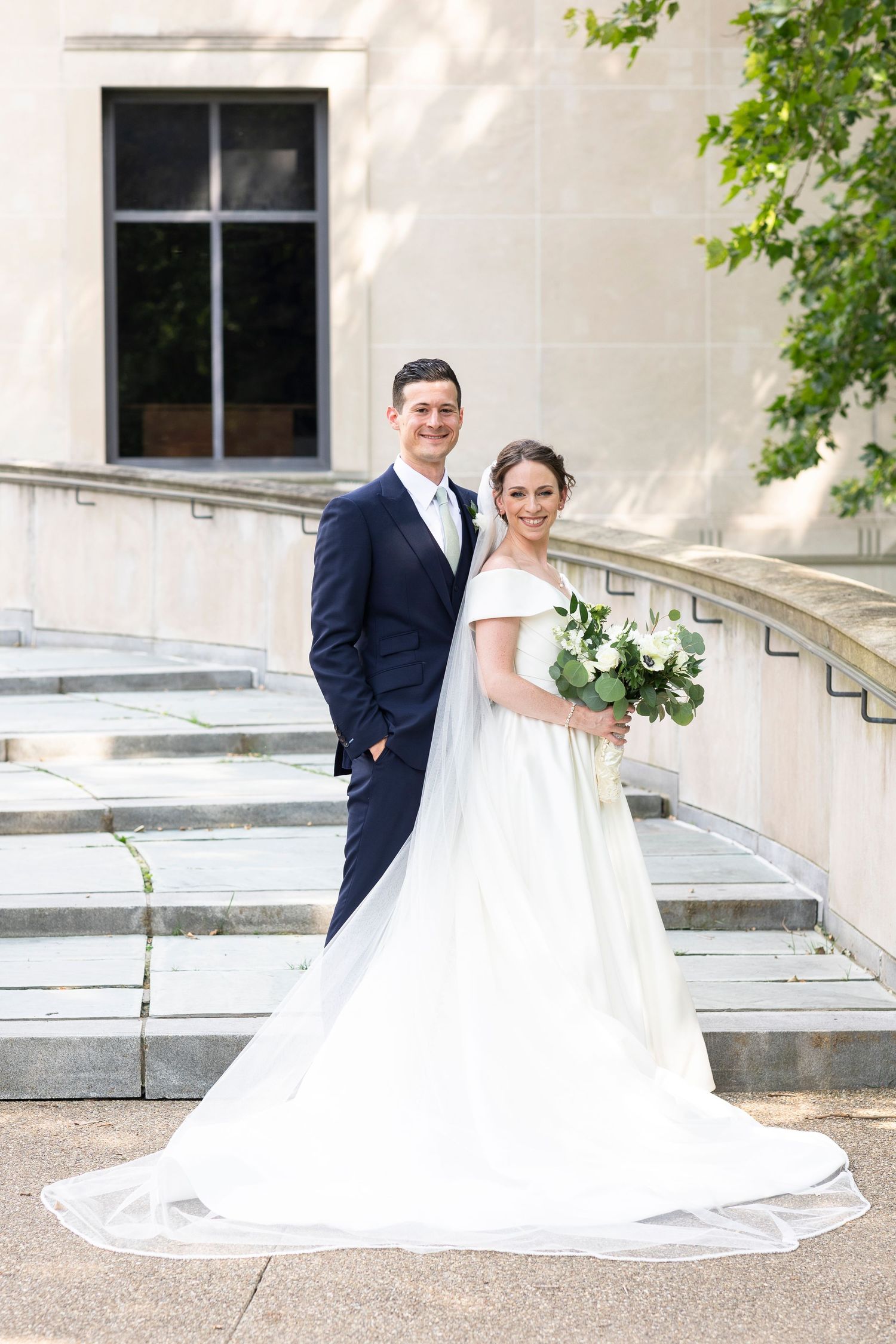 Elegant wedding portrait on stone steps with classic architecture and natural lighting.