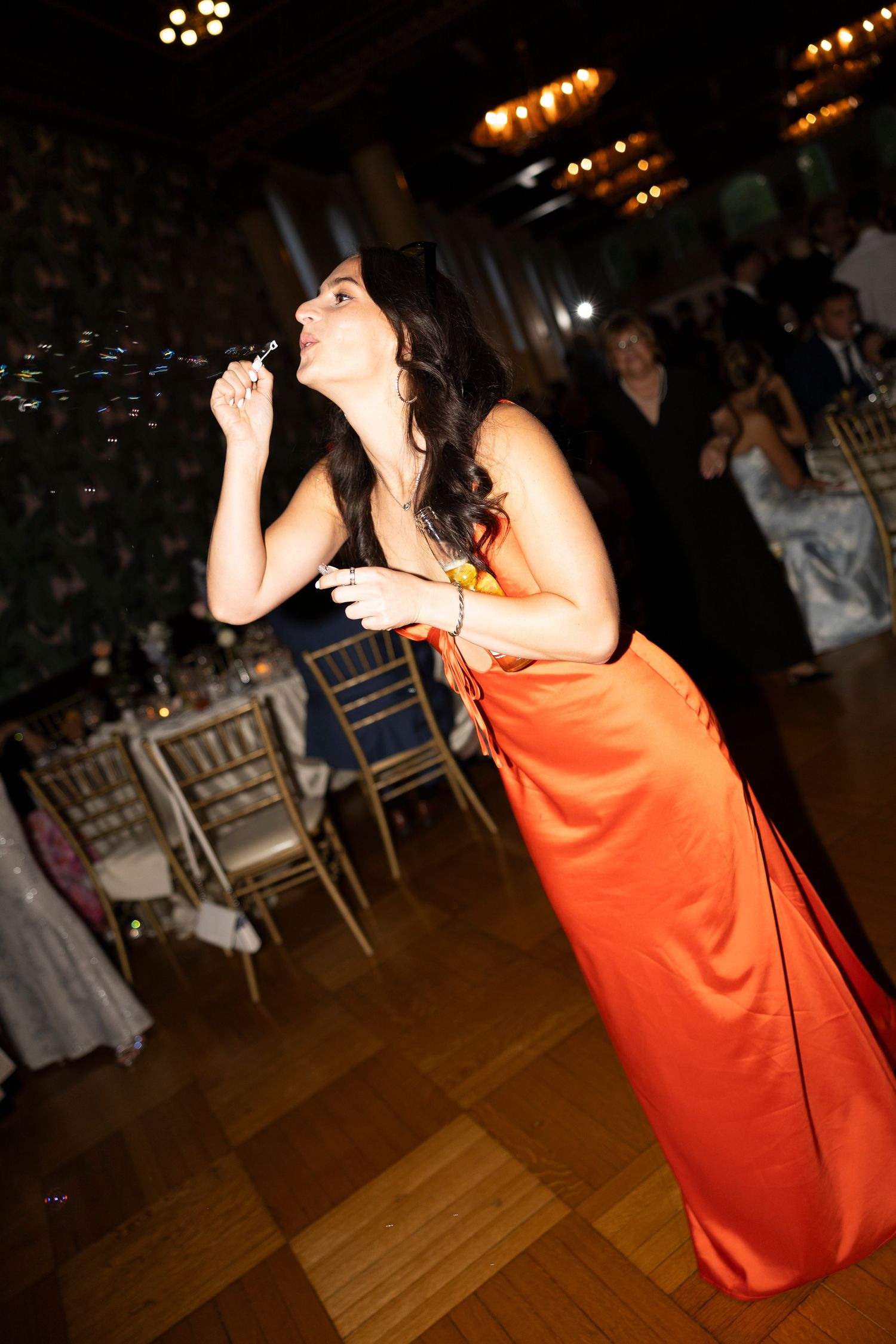 Singer in orange dress performing at an indoor event.