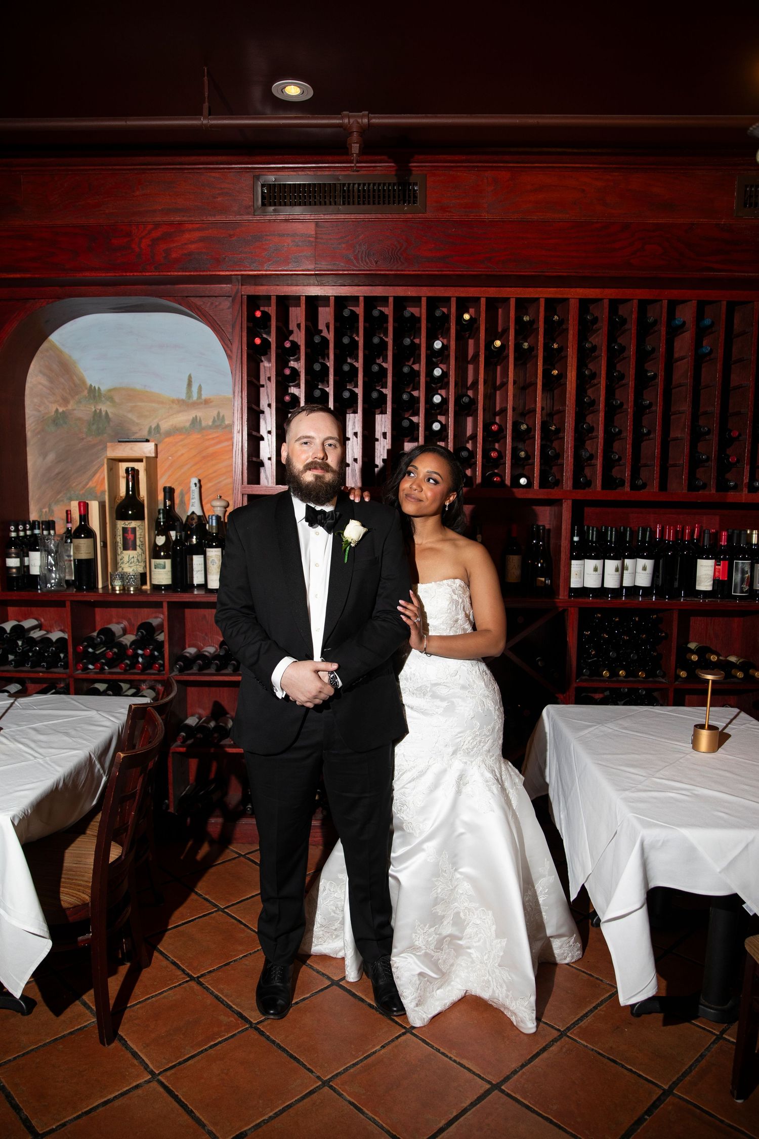 Couple sharing intimate moments in front of a rustic wine cellar backdrop.