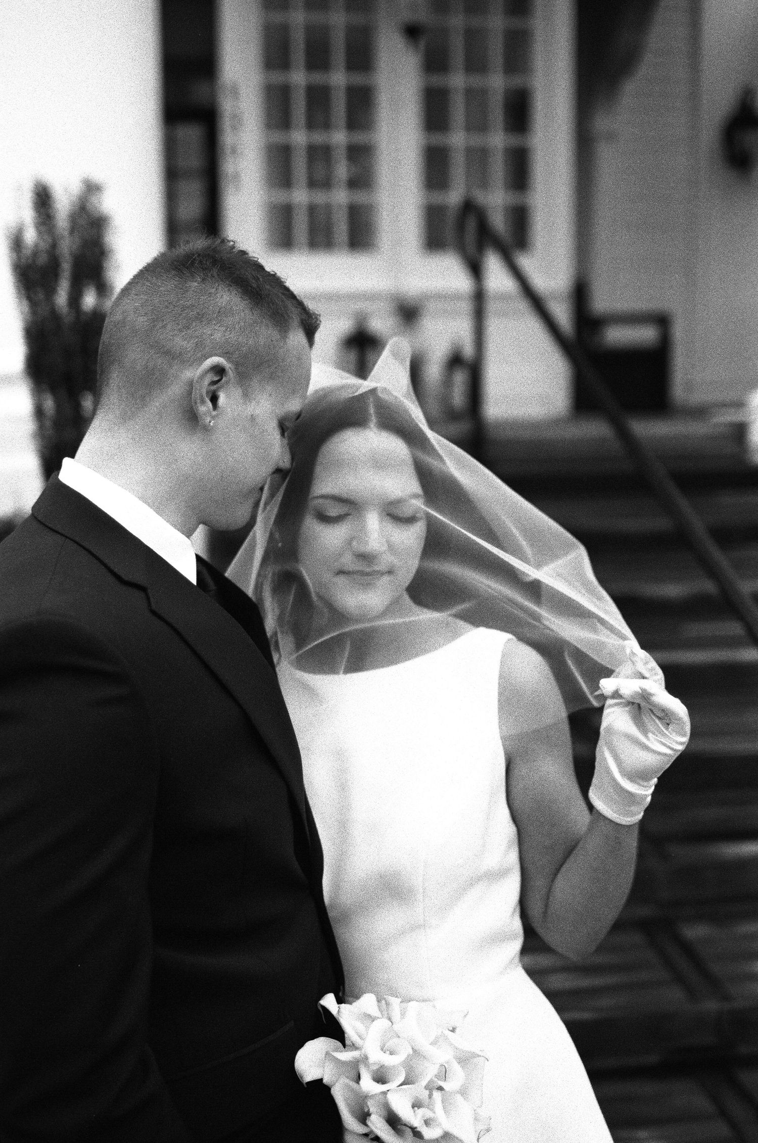 Black and white wedding photos showing romantic kiss sequence between bride in white dress and groom in dark suit.