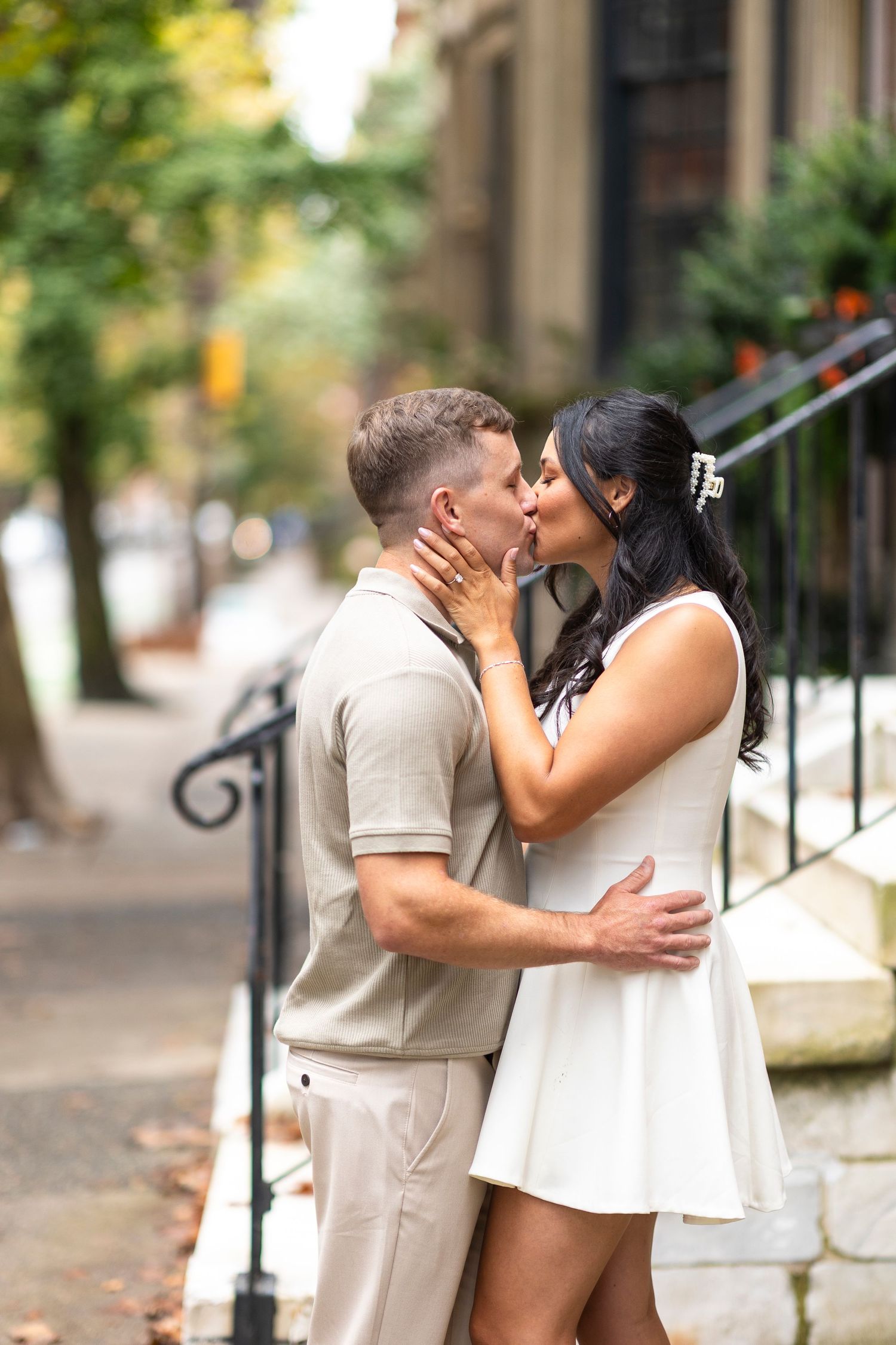 Romantic autumn engagement photos on tree-lined city street with warm lighting.