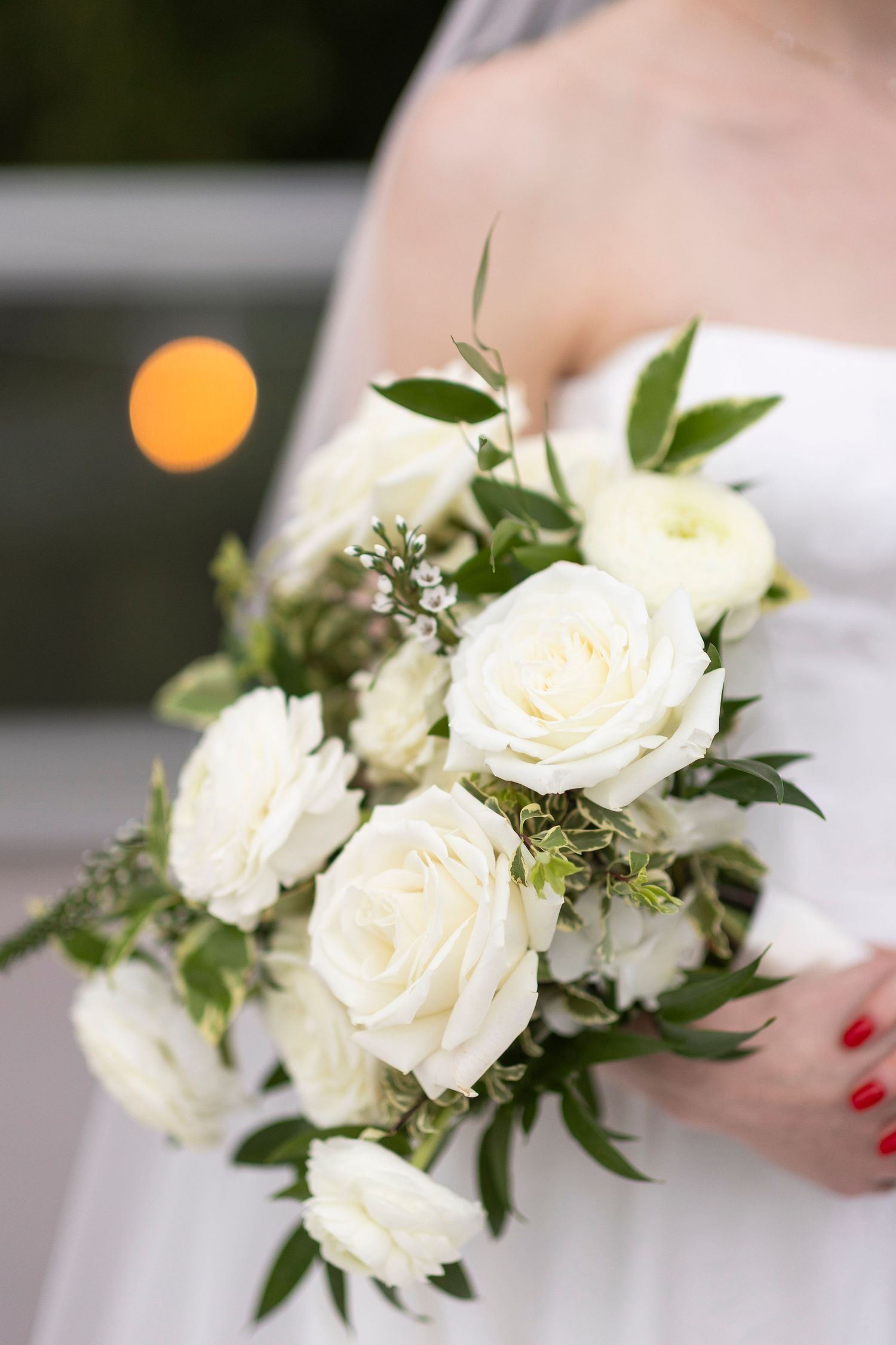 An elegant white rose and greenery wedding bouquet with delicate details.