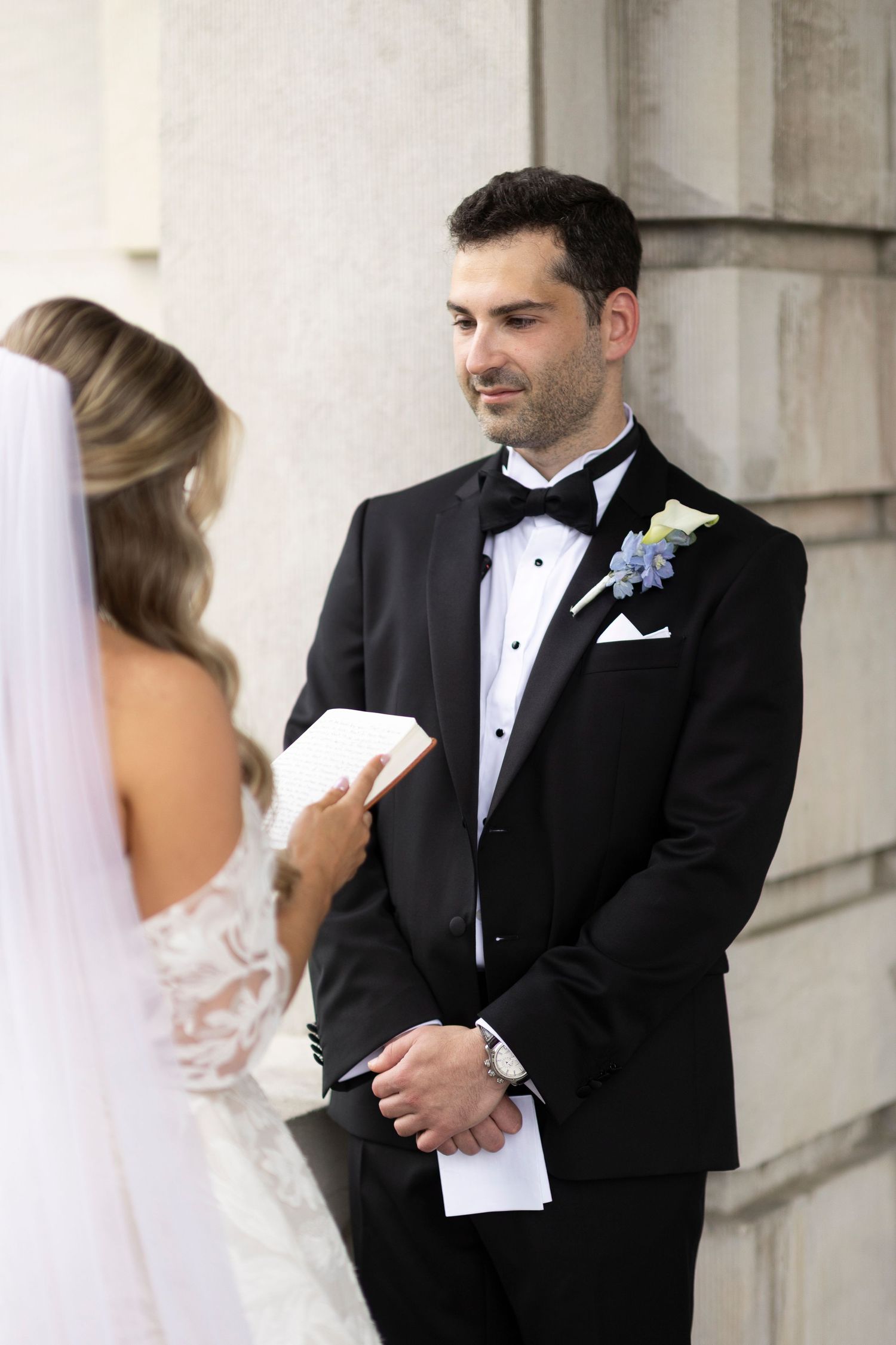 A couple shares an intimate first look moment during their wedding, exchanging notes in formal attire.