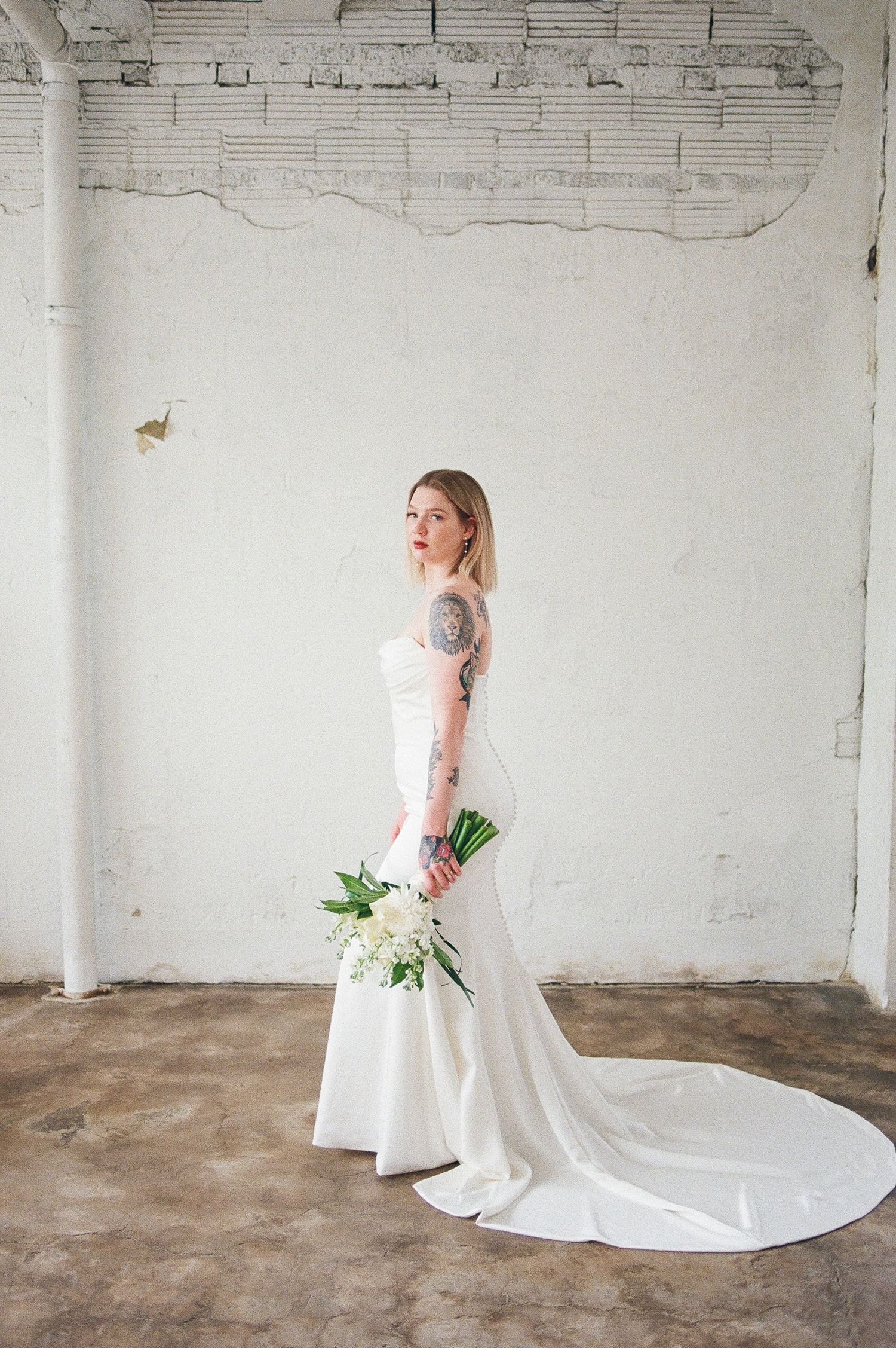 Elegant bridal portraits in a minimalist industrial space featuring a flowing white wedding gown with train.