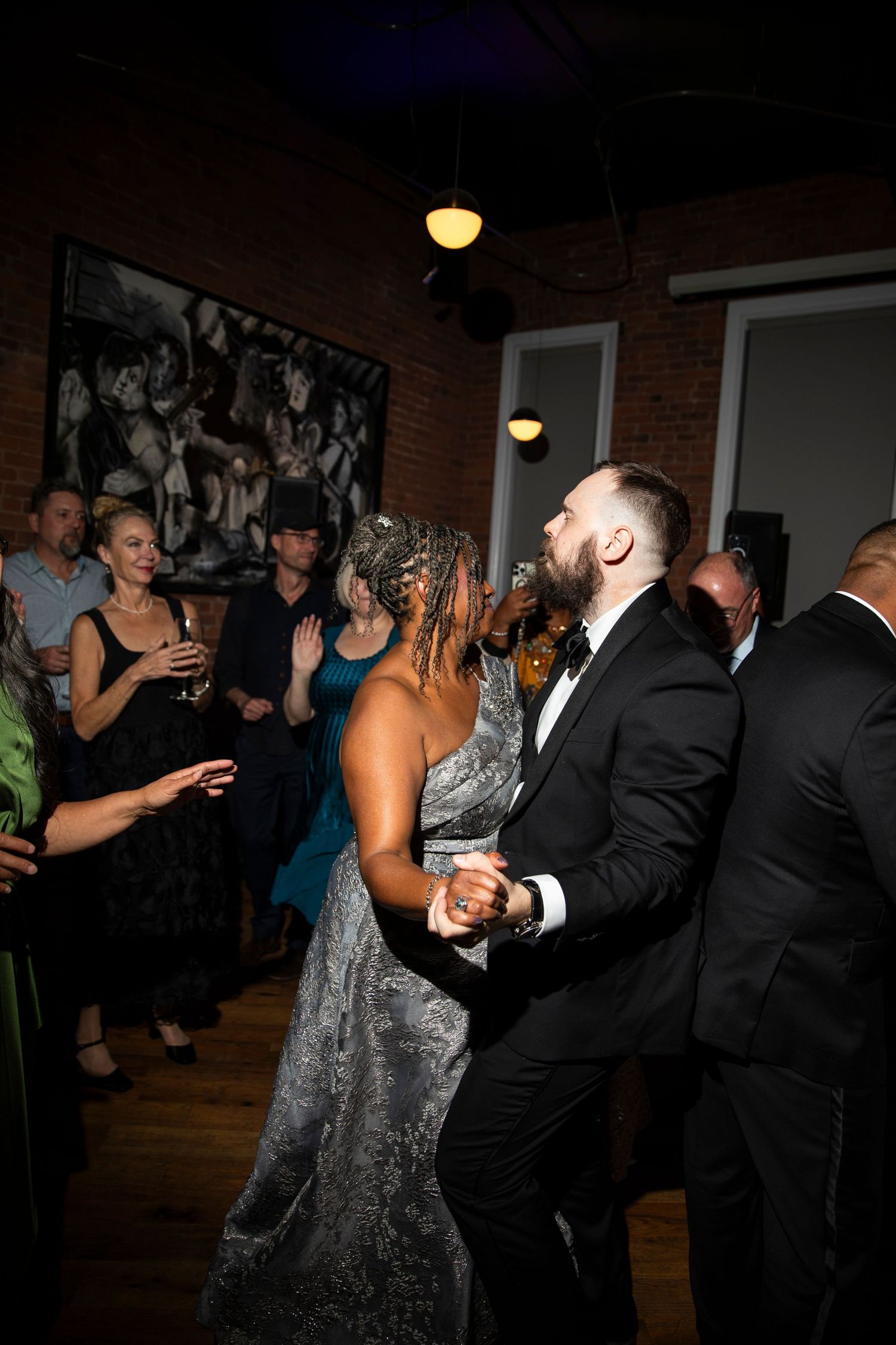 Wedding reception guests dancing and socializing in a dimly lit venue.