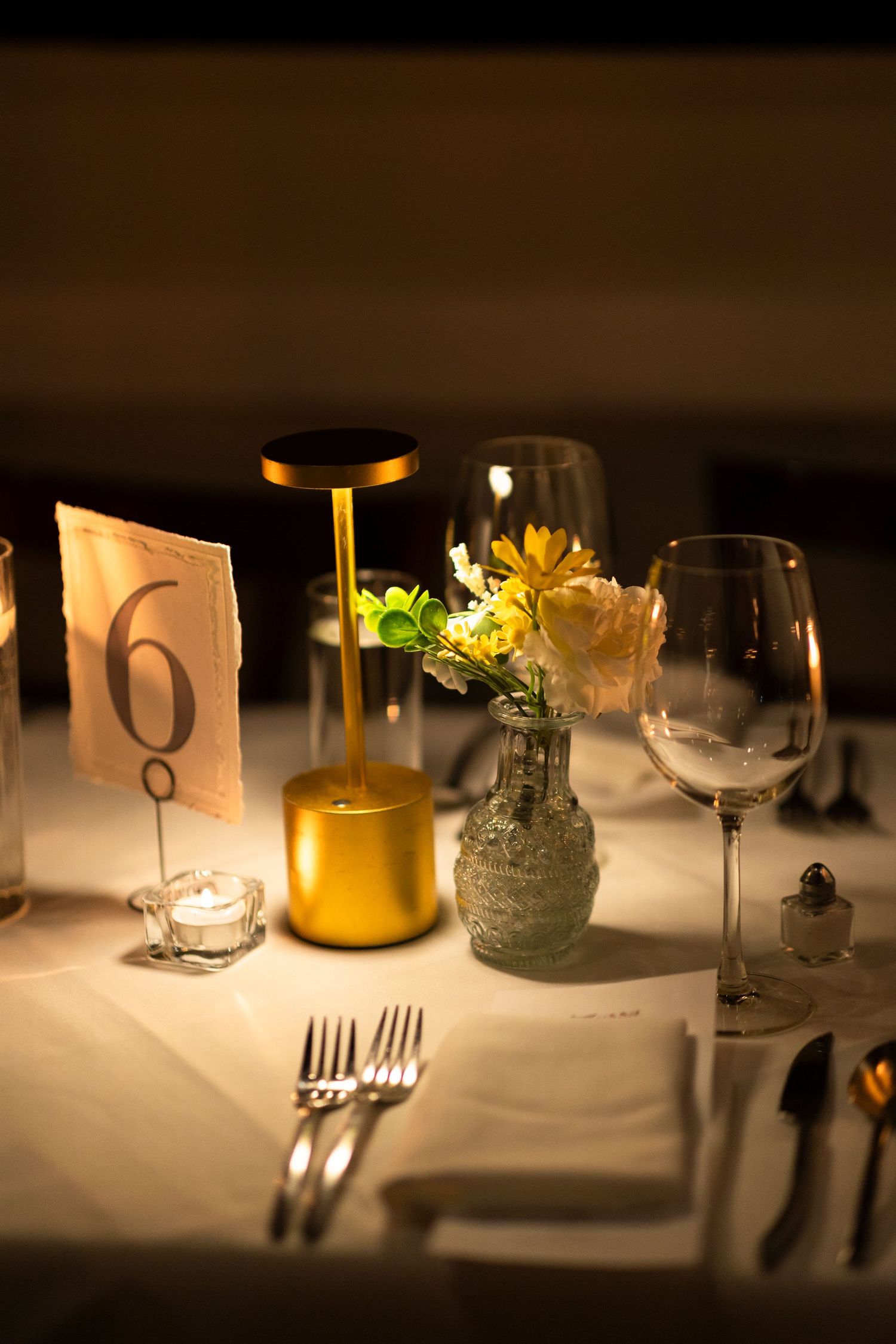 Intimate table setting with glassware and candlelight creating warm ambiance.
