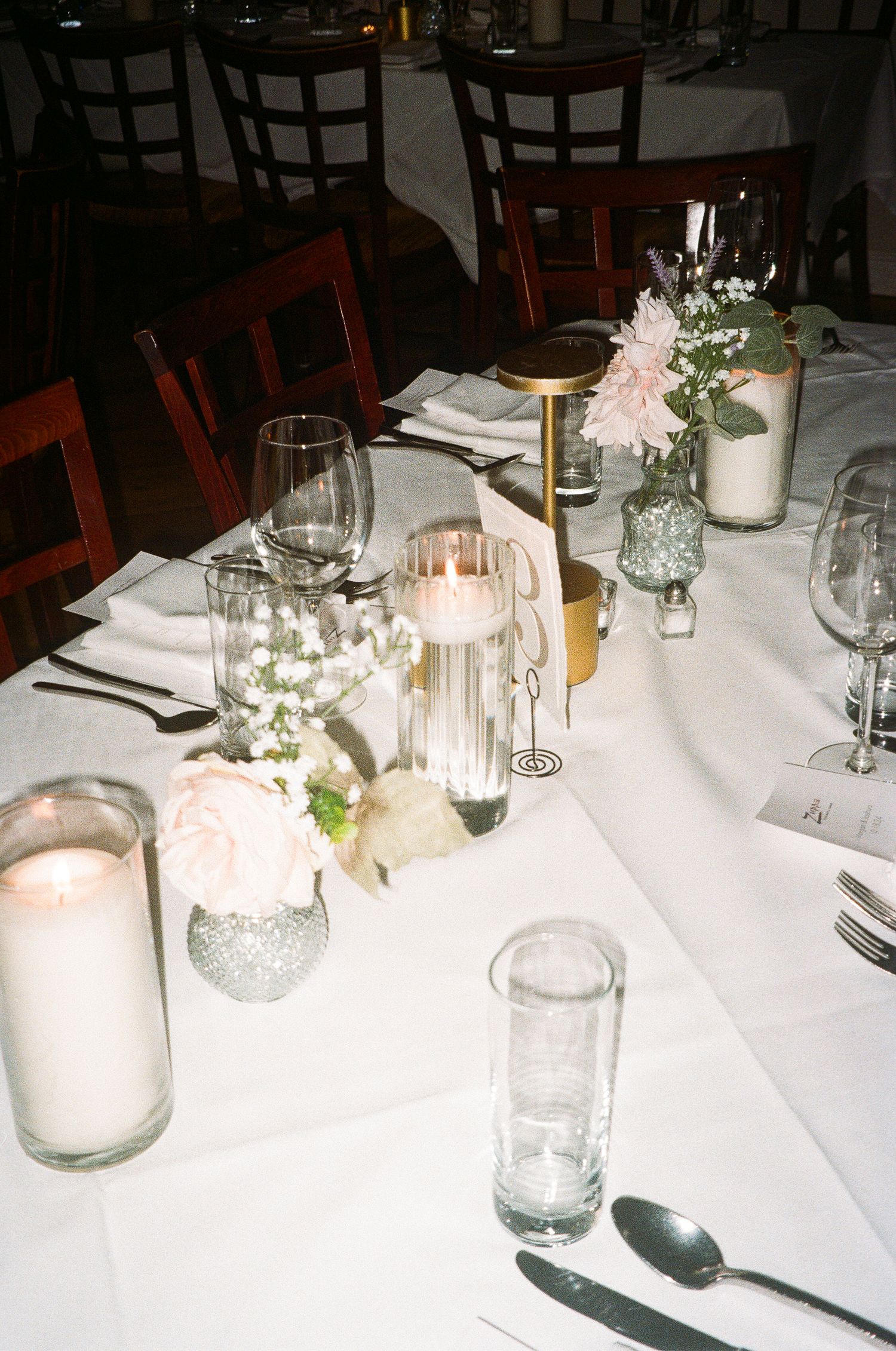 Elegant wedding reception table with white linens, glassware and candlelight centerpieces.