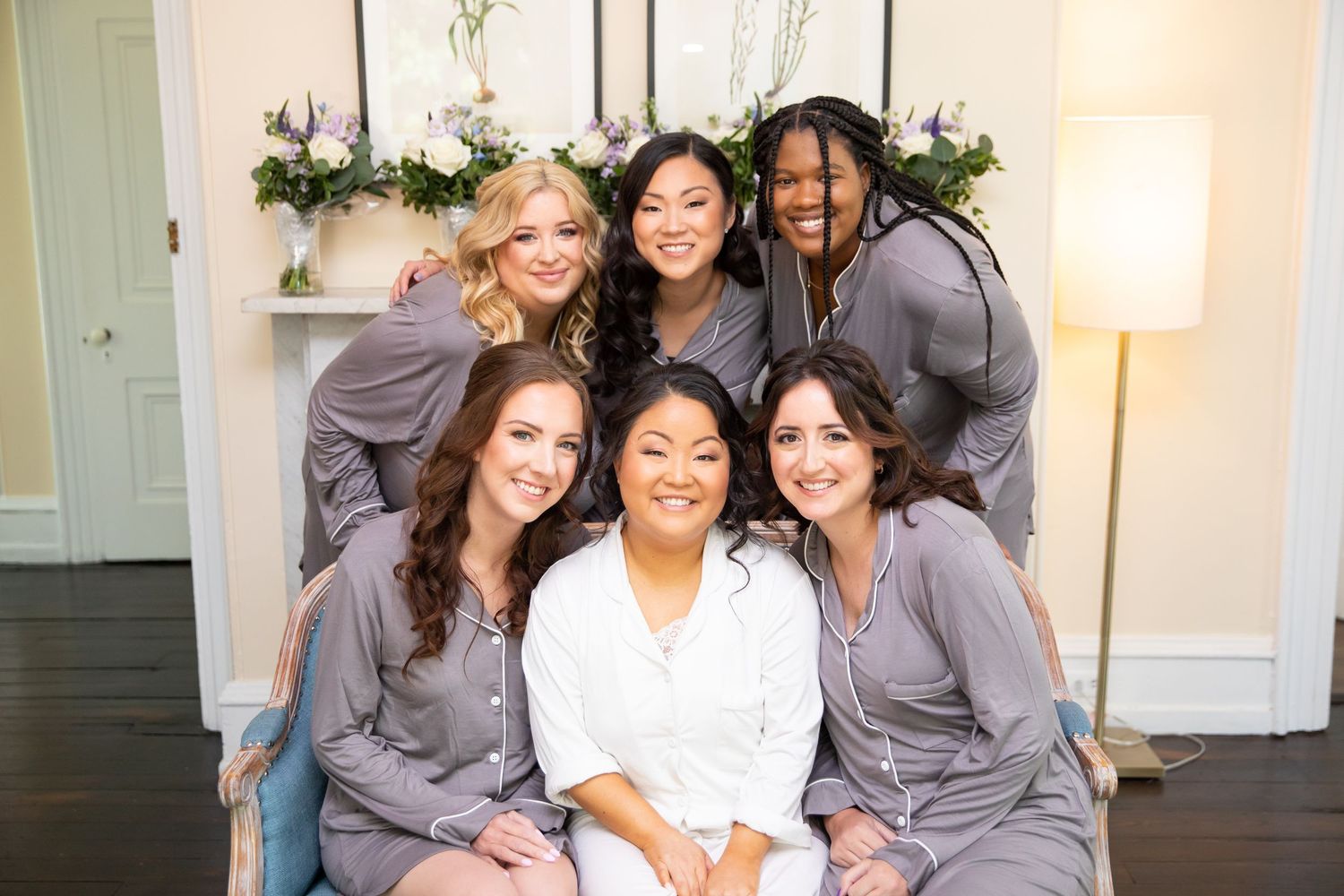 A group wearing matching gray robes sits together during wedding preparations.