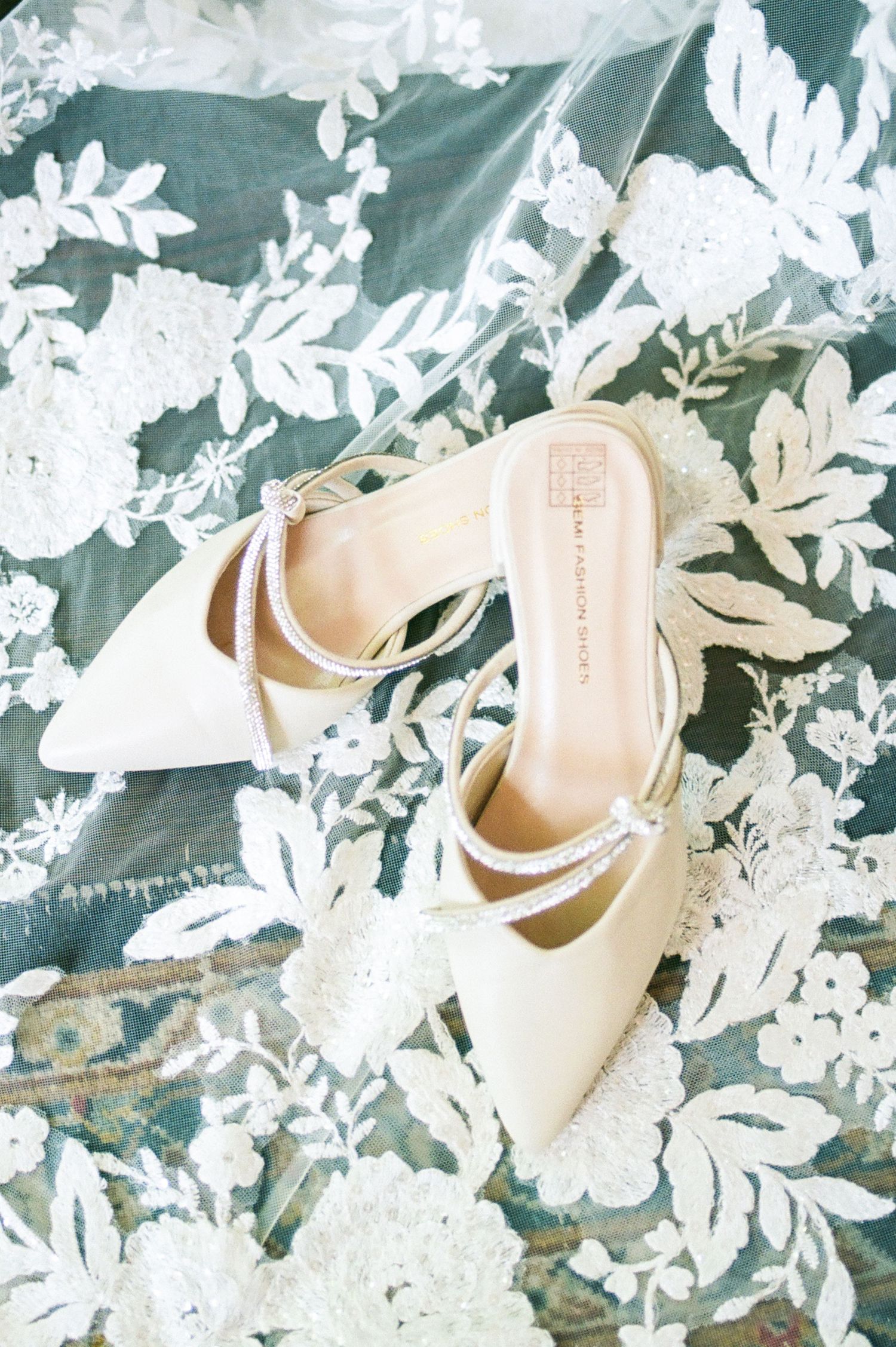 Ivory bridal shoes arranged on a floral patterned background.
