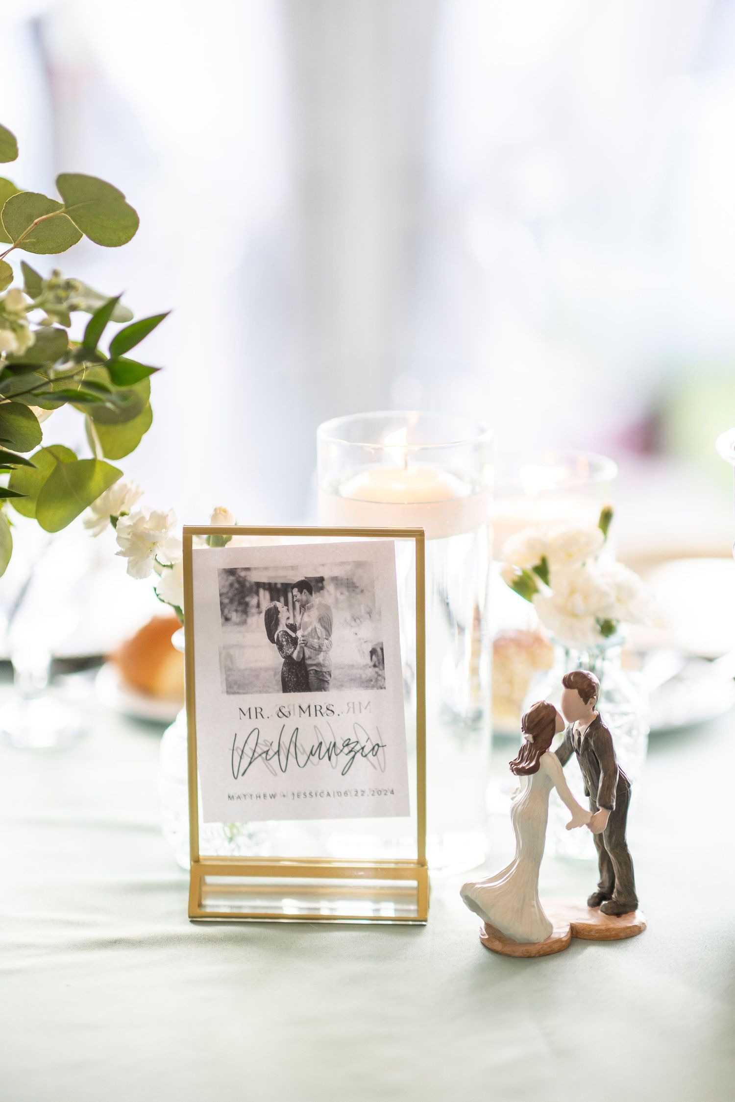 Wedding reception table details with framed photos and decorative figurines.