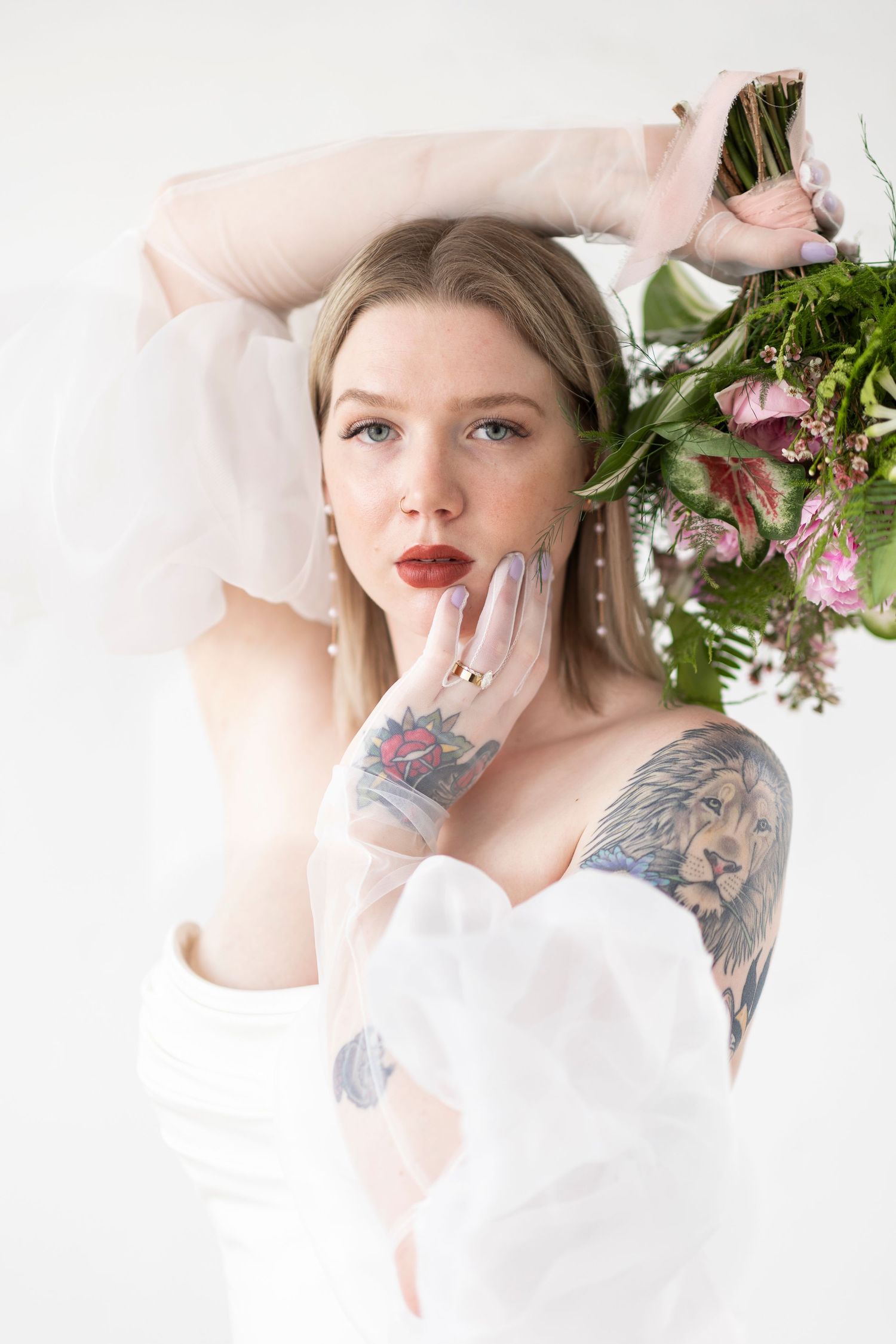 Artistic portrait with white fabric and pink floral arrangement.
