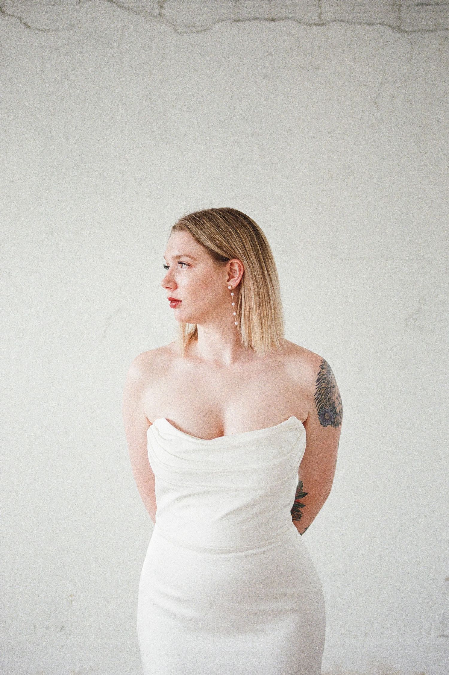 Modern bridal portraits against white wall showcasing minimalist style and elegant pose.