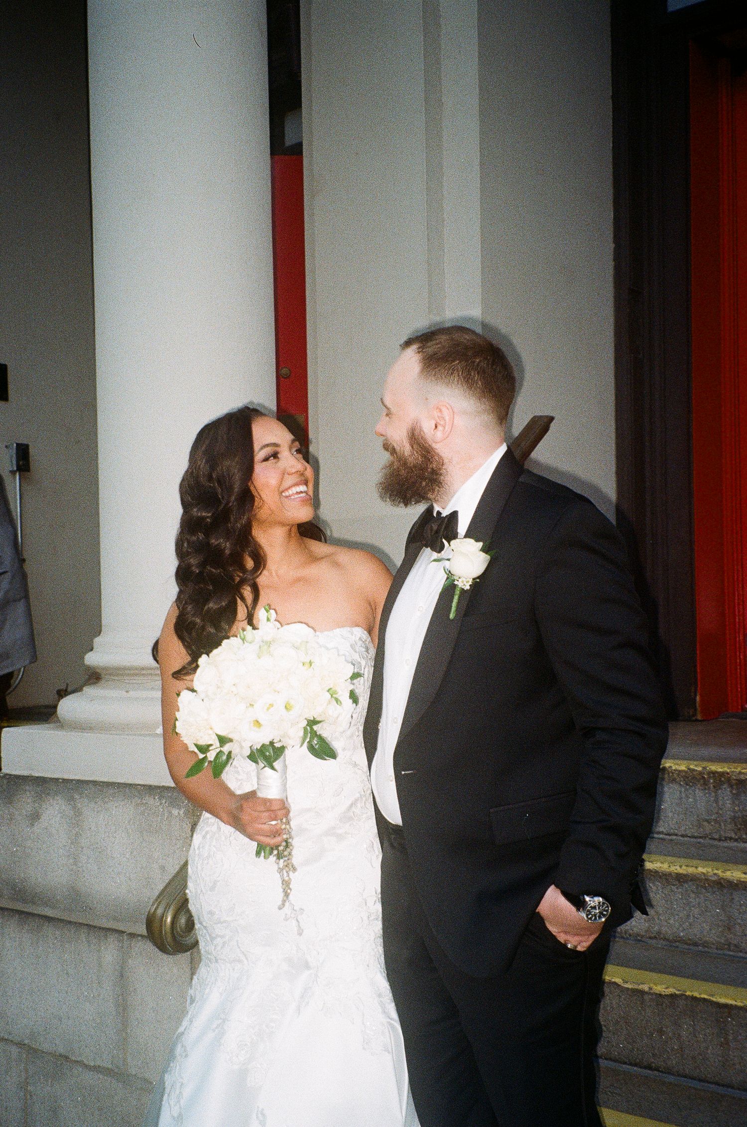 A couple shares a joyful moment outside on their wedding day.