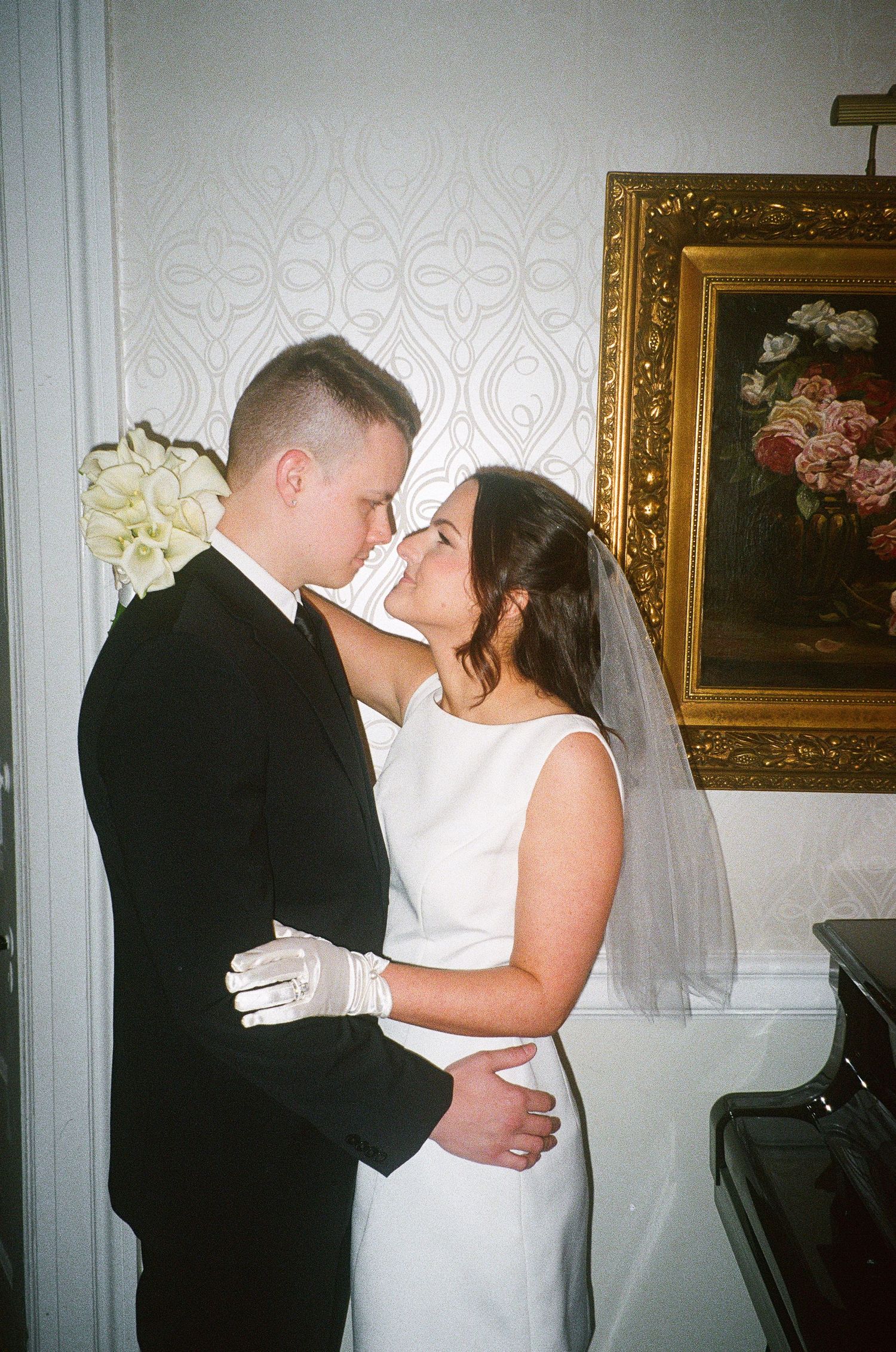 Romantic moment captured in room with ornate gold-framed artwork.