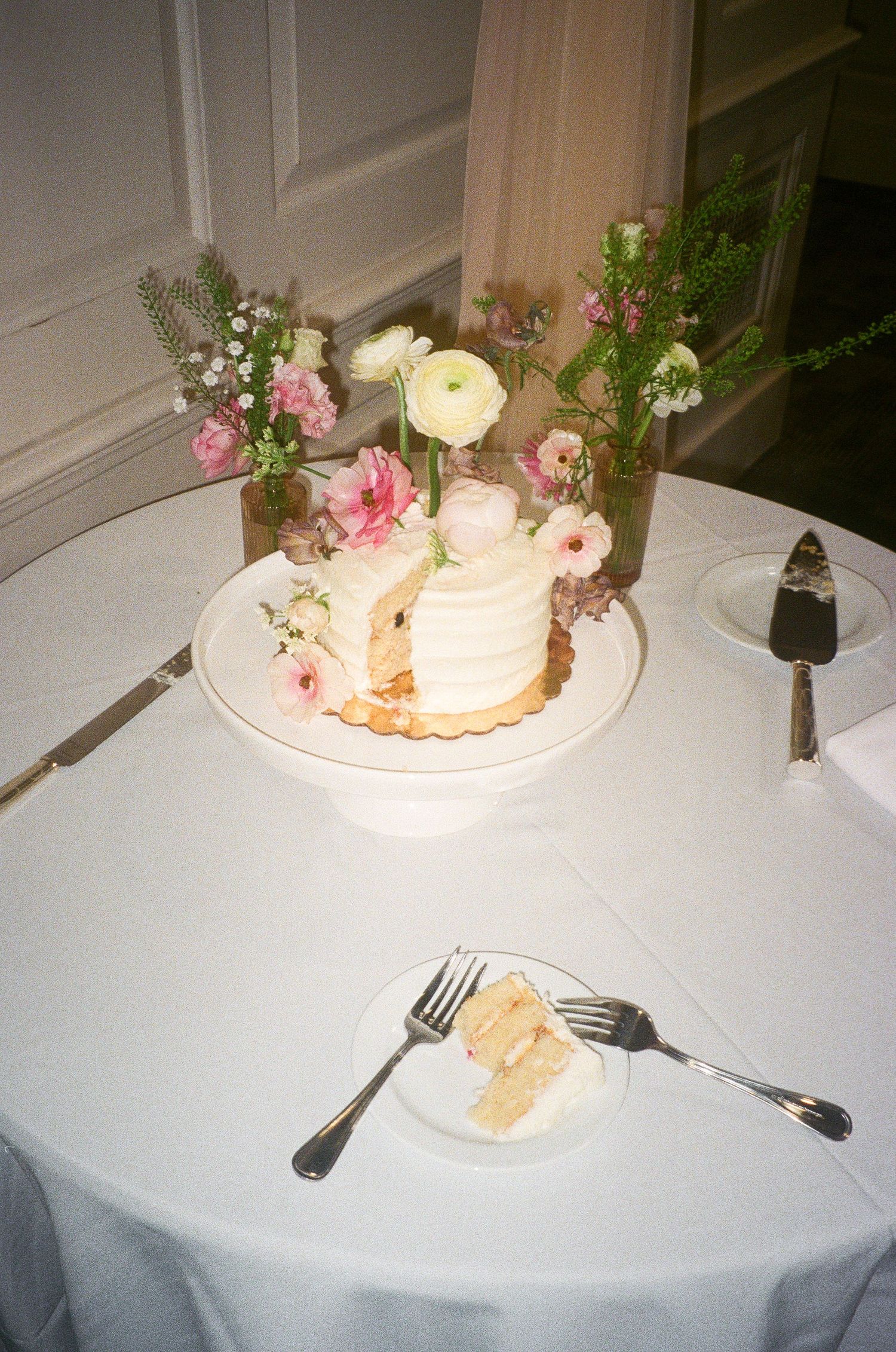 Wedding cake slices on white plates with floral decorations at an elegant reception.