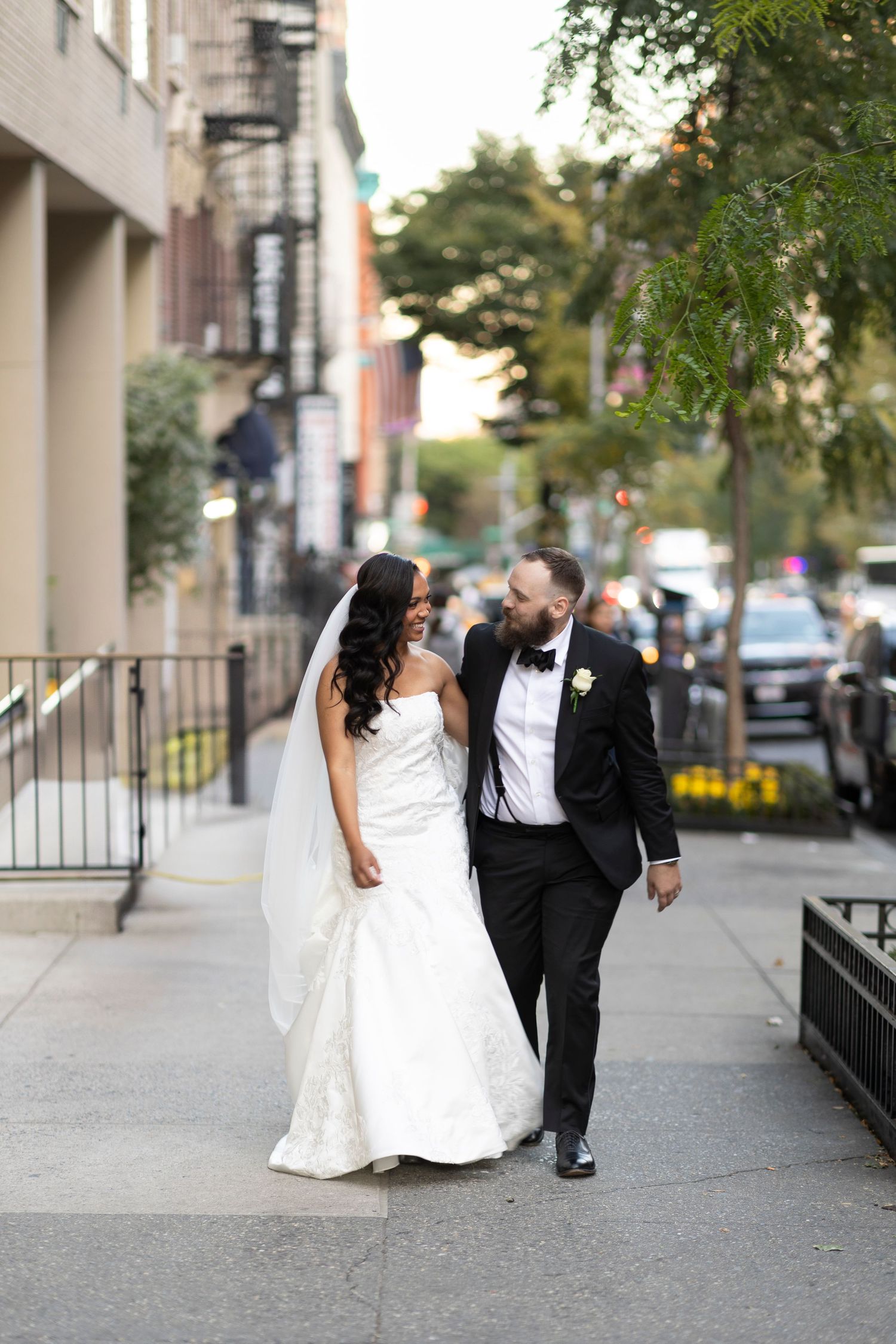 Candid wedding portrait of couple walking together on urban sidewalk.