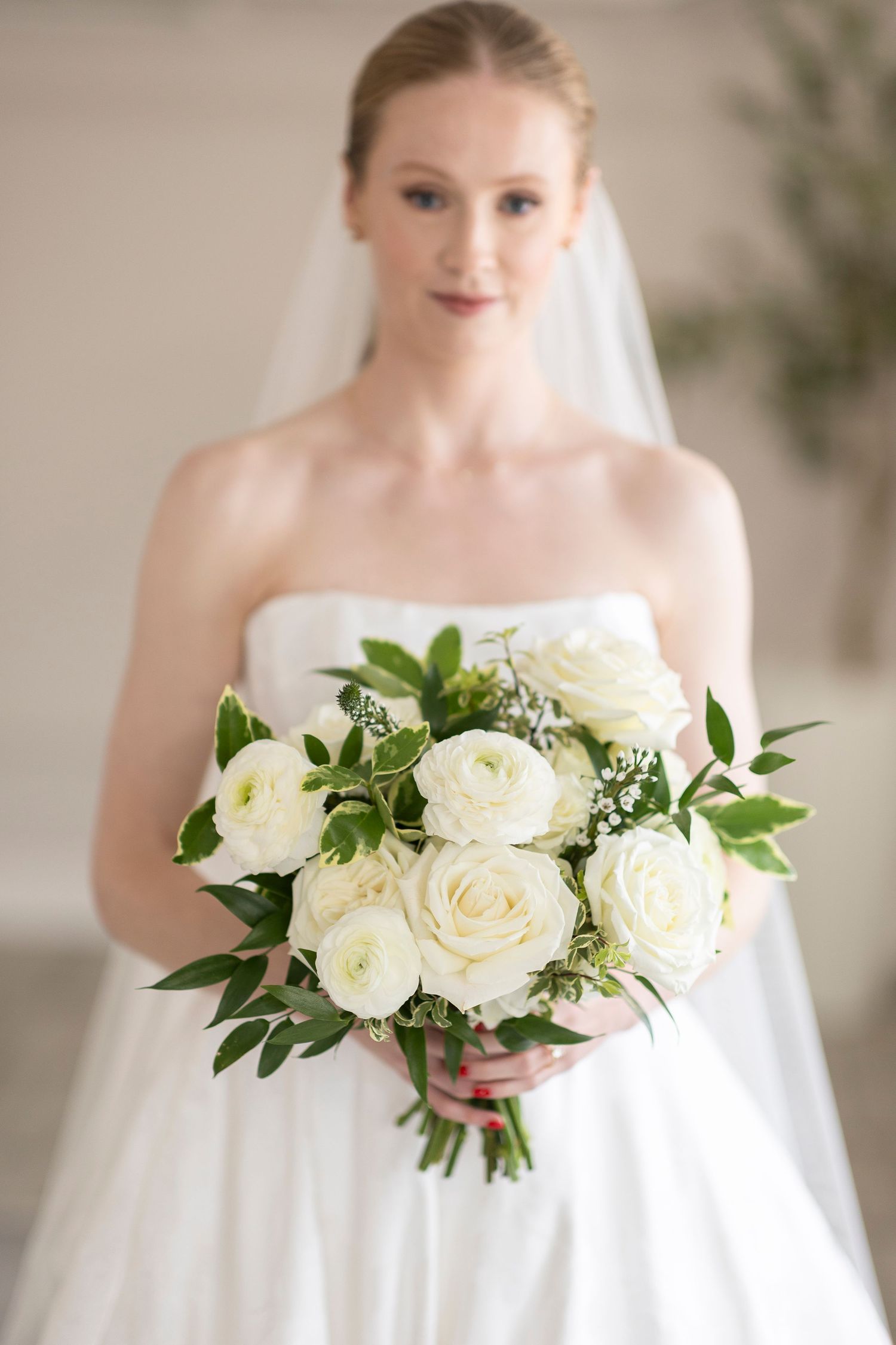 Classic white rose wedding bouquet with fresh greenery complementing traditional bridal gown.