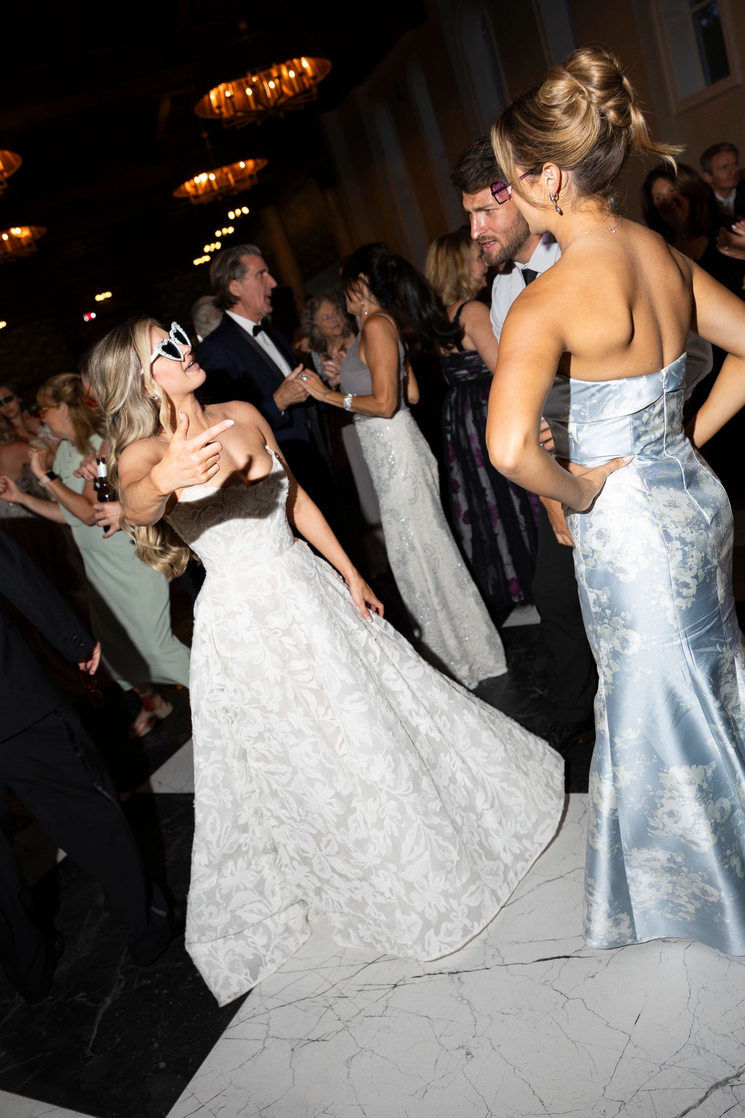 Couples dancing at a wedding reception with a bride in a white gown and bridesmaid in light blue dress.