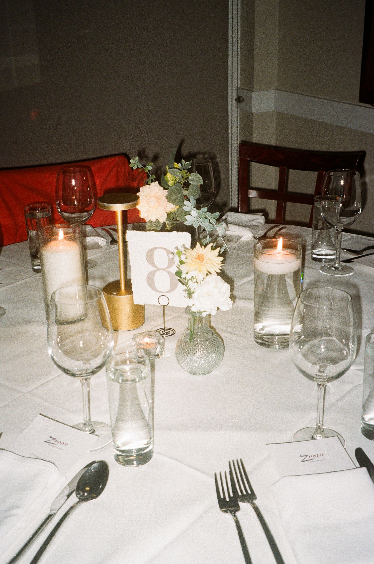 White table setting with candles, flowers and glassware for a formal dinner party.