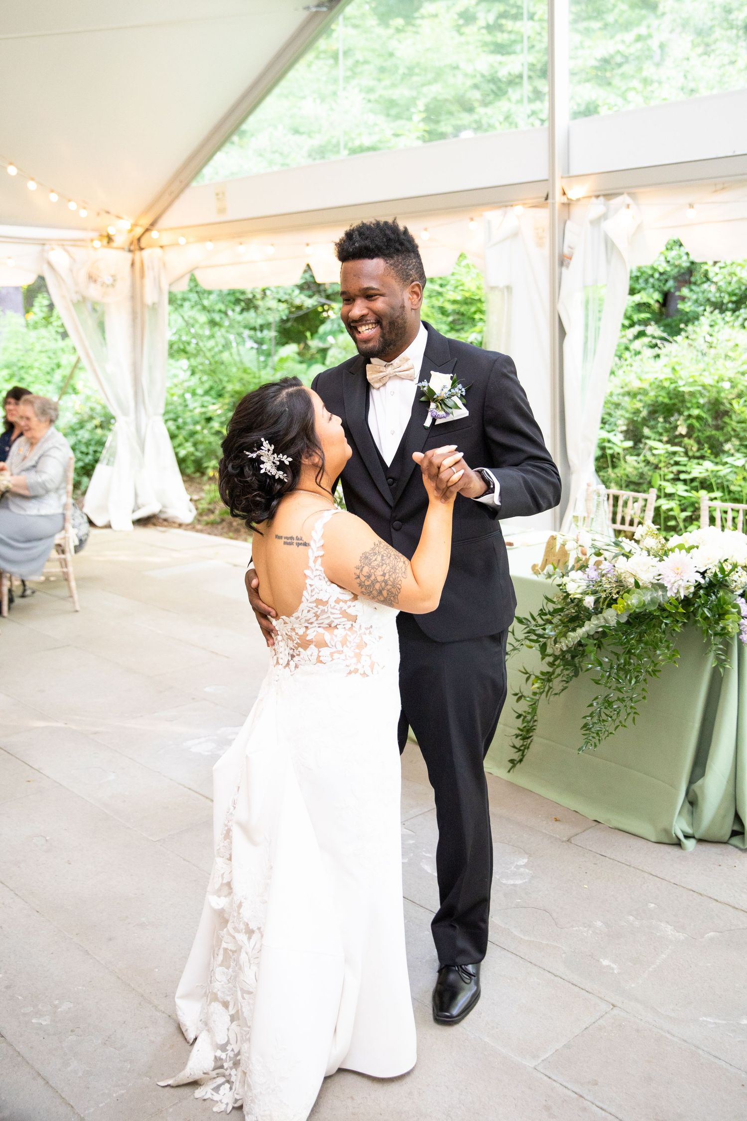 Wedding couple dances and celebrates under an elegant white tent reception.