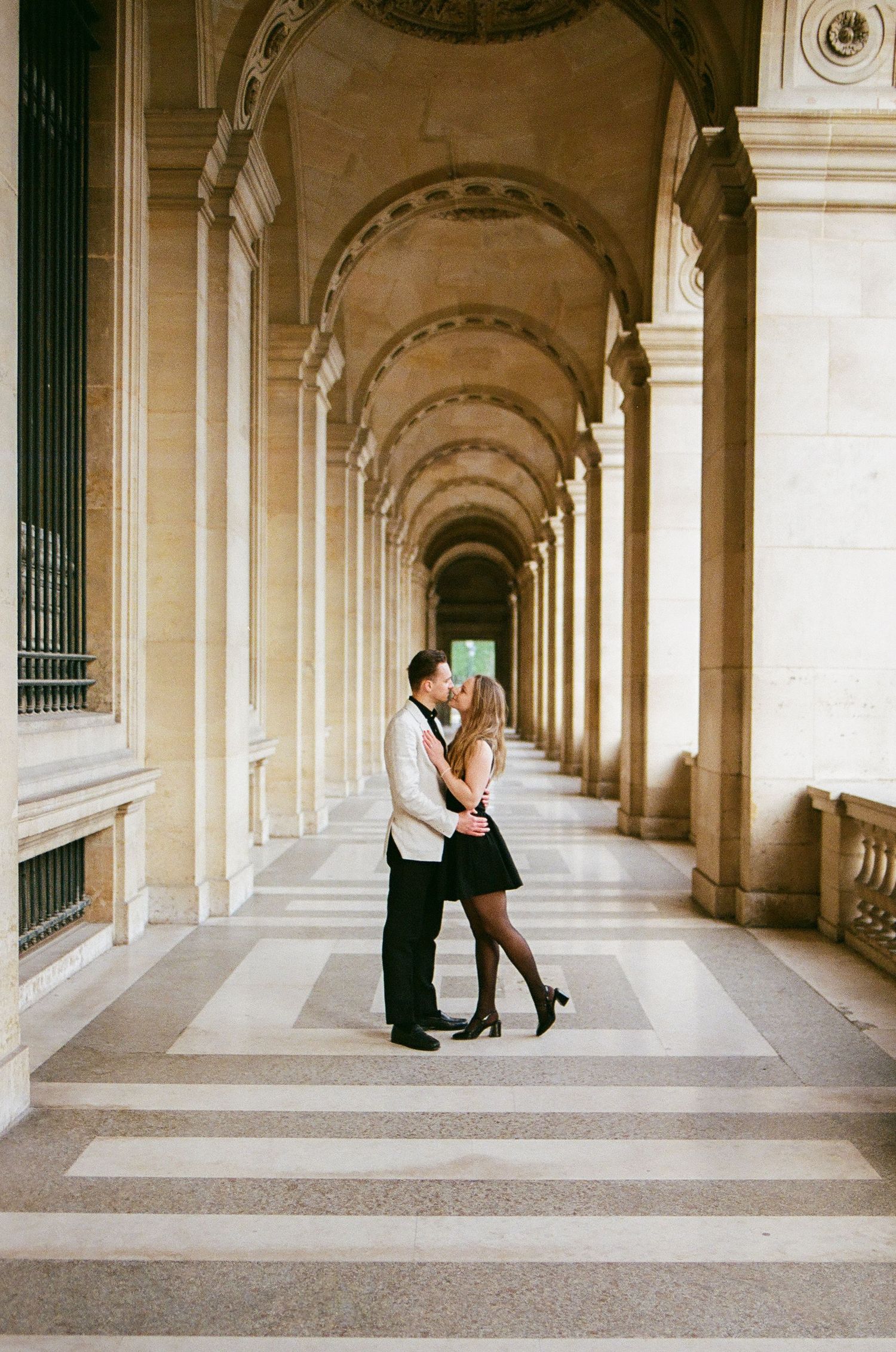 Elegant arched colonnade hallway with white stone columns creates a romantic architectural backdrop.