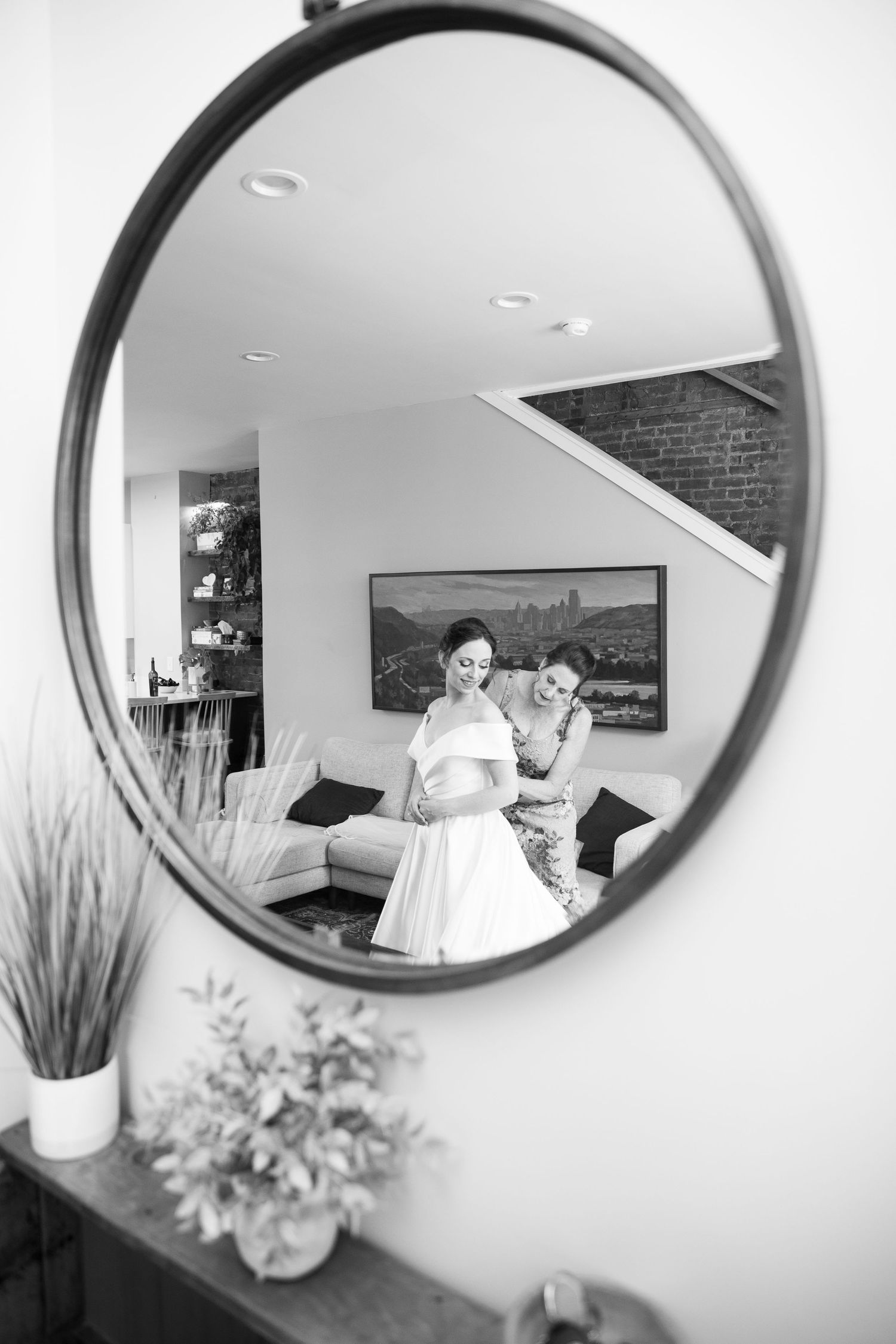 Round mirror on white wall reflecting wedding preparations in a modern room.