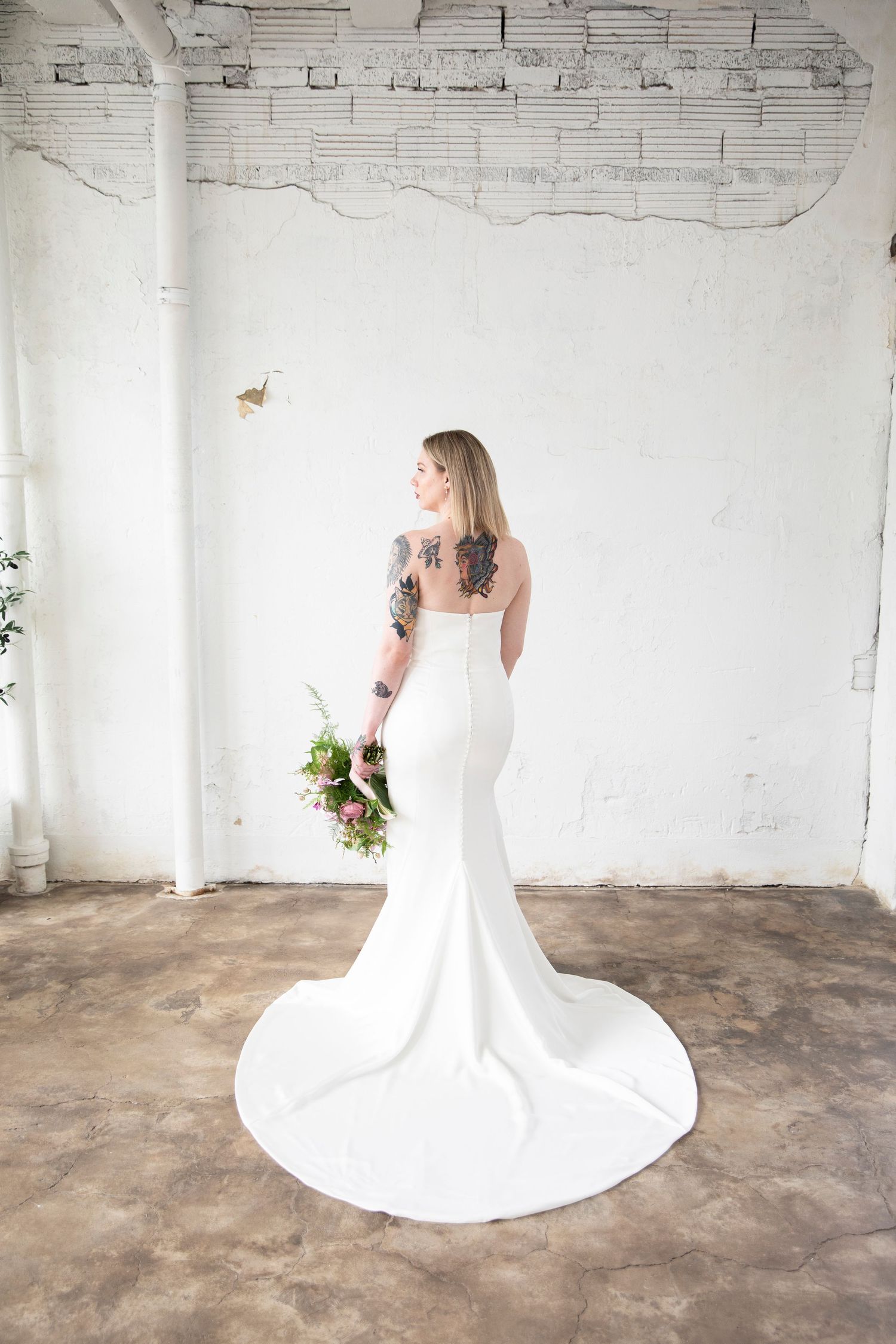 Full-length bridal portraits showing flowing white gown train in industrial space.