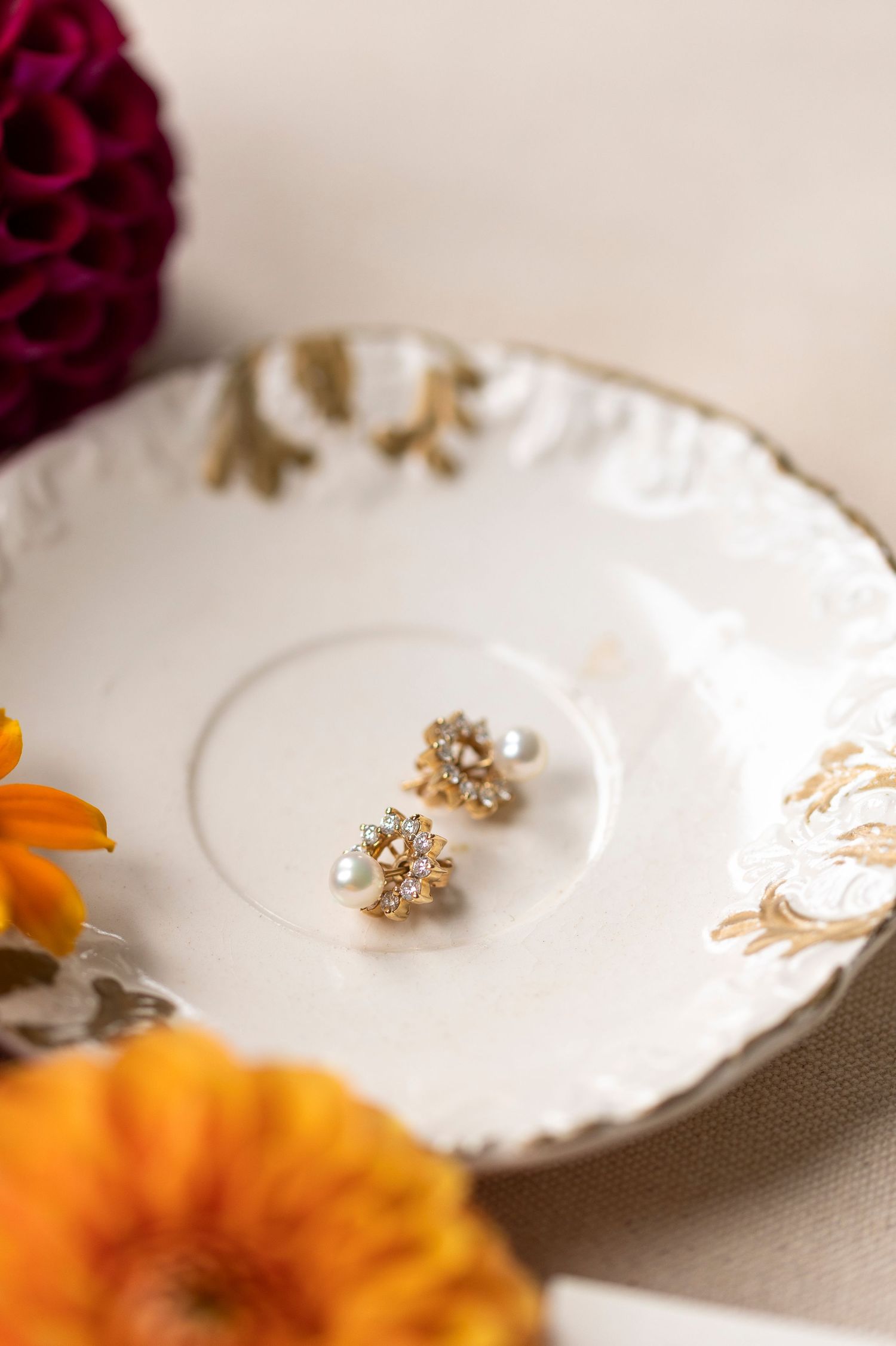 Pearl and crystal earrings displayed on delicate white china plates with gold accents.
