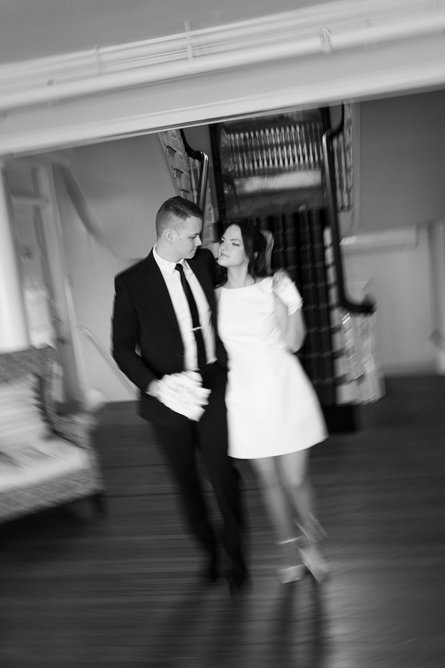 A blurred motion black and white photo of a couple dancing in an elegant indoor setting.