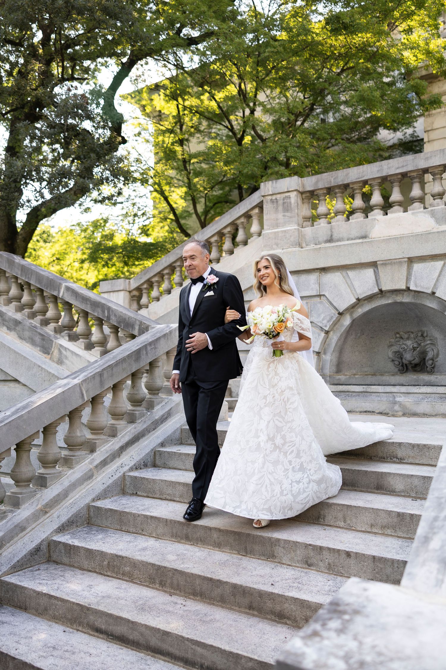 A couple shares a joyful moment on grand stone steps during their wedding day.
