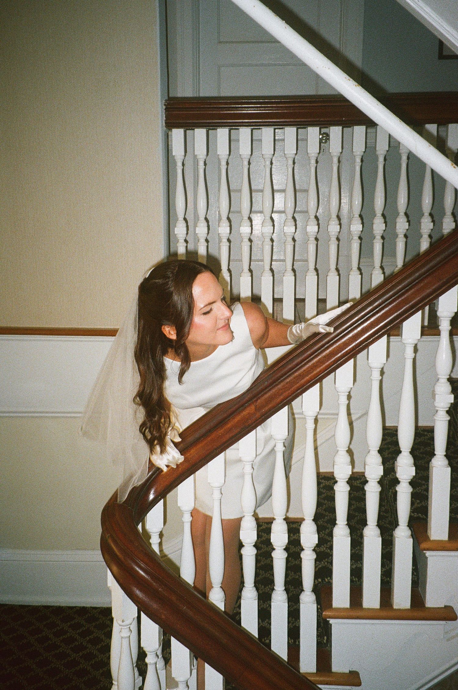 White staircase with wooden banister and ornate spindles in natural light.