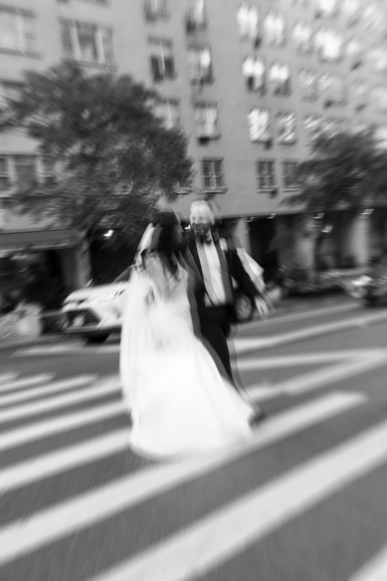 Motion blur photograph of a white wedding dress swirling against an urban background.