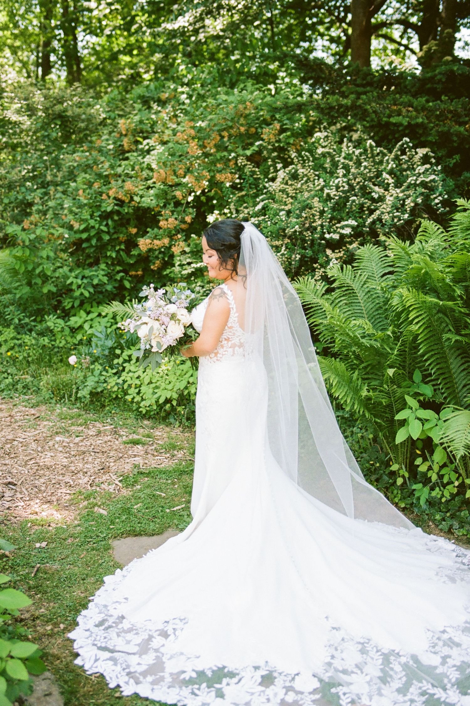 Beautiful bridal gown with cathedral train photographed in a lush garden setting.