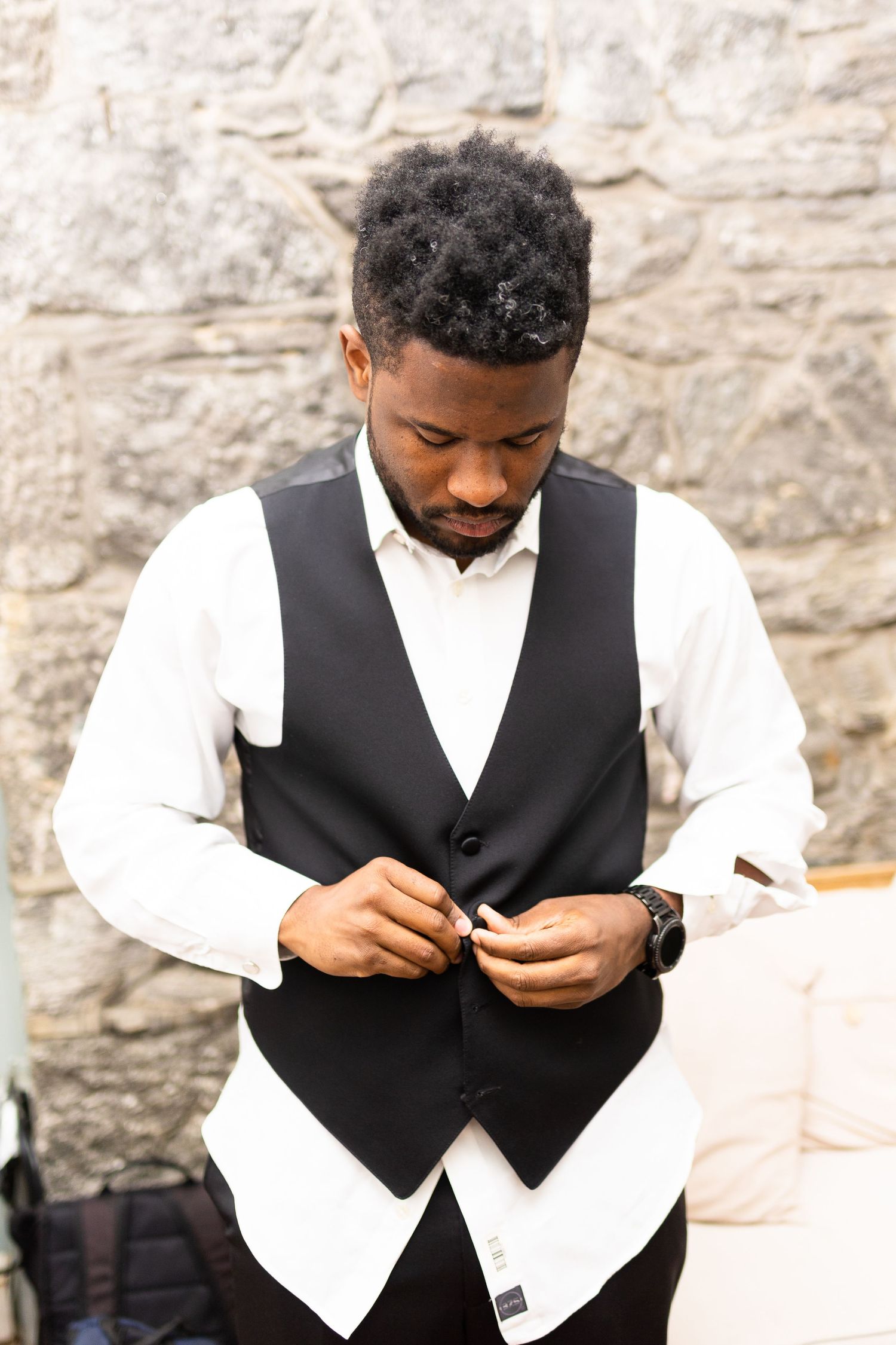 A person in formal attire adjusts their outfit while getting ready.