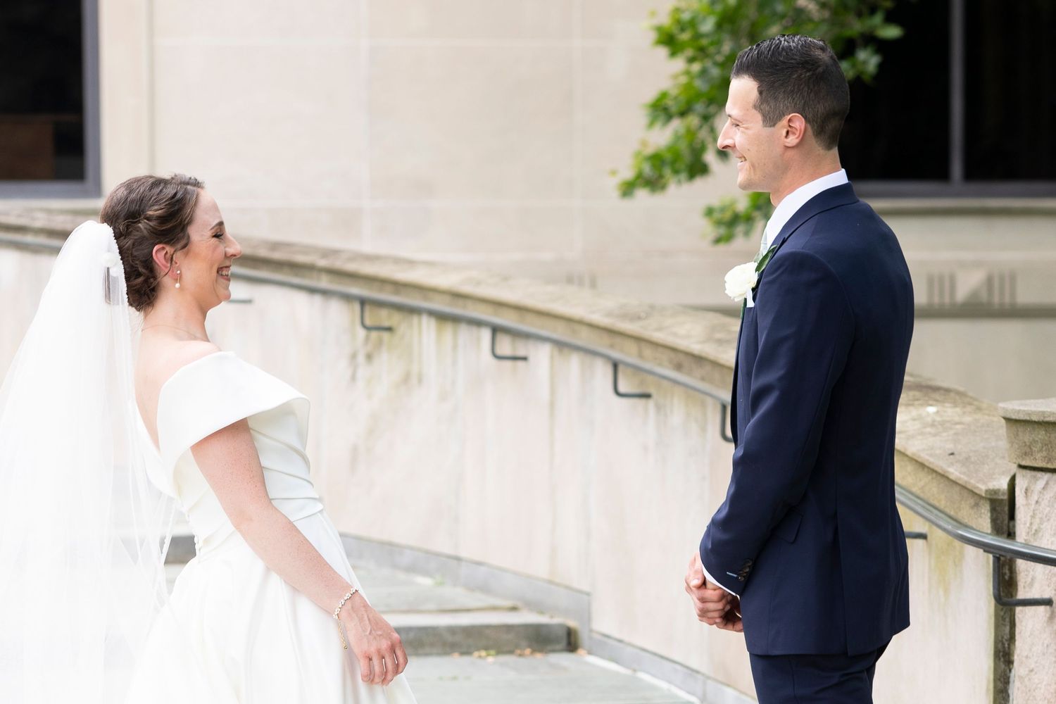 Candid moment between newlyweds on elegant stone steps of a historic building.