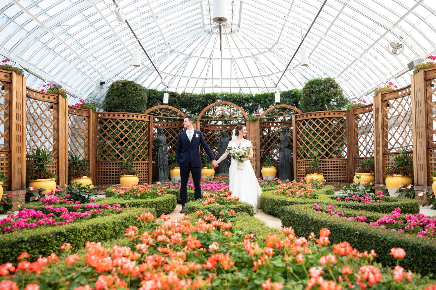 Greenhouse garden venue with wooden pergolas and bright orange tulip displays.