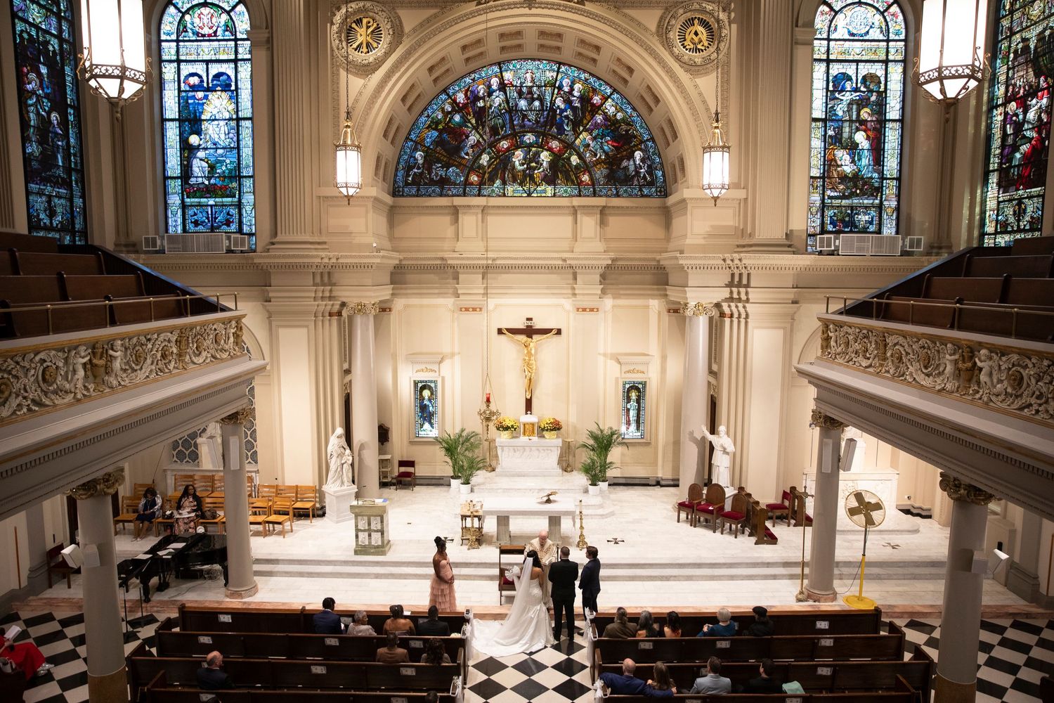 Interior of grand church with stained glass windows, vaulted ceilings and ornate architectural details.