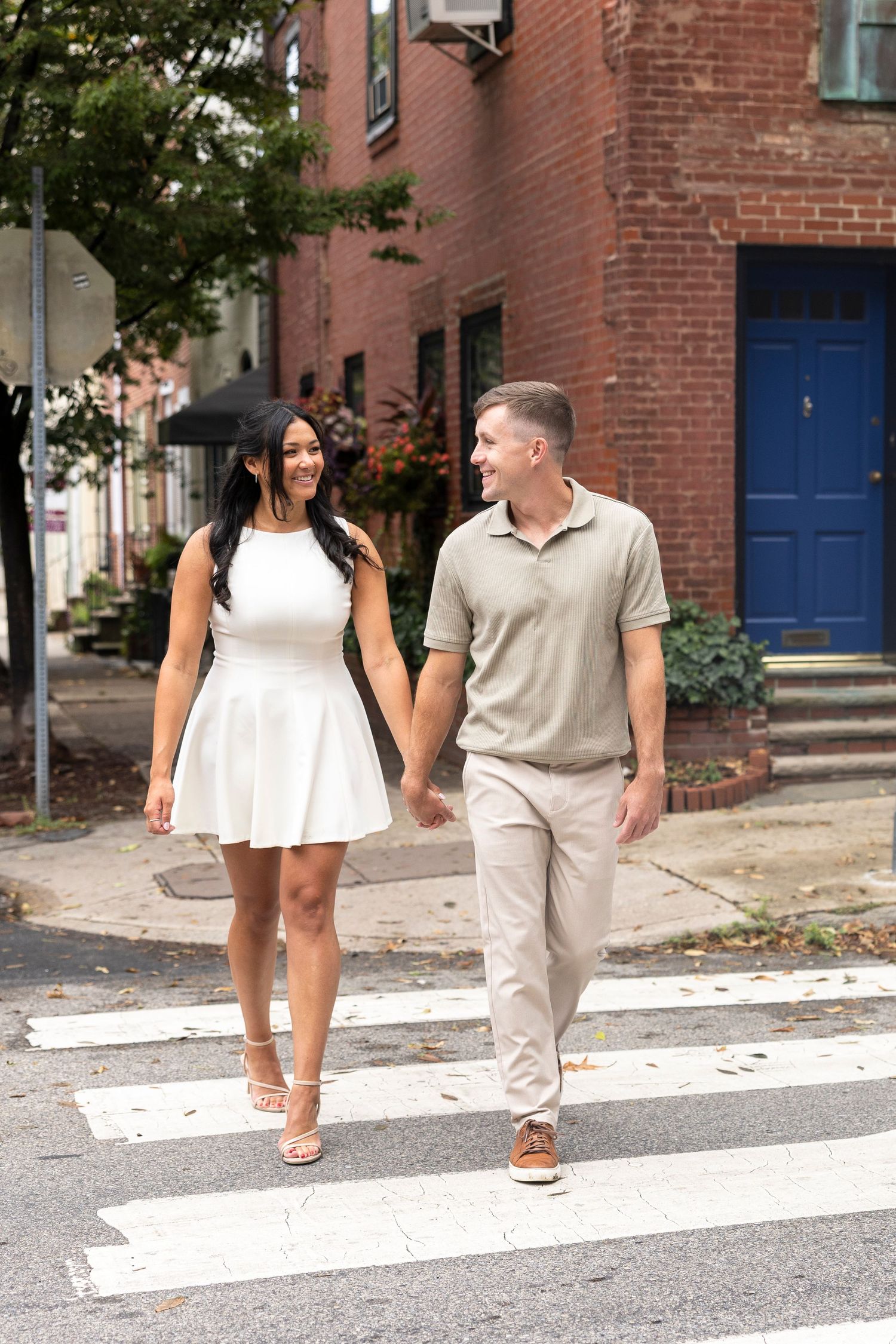 A couple crosses a street in coordinated outfits with their dog following behind.