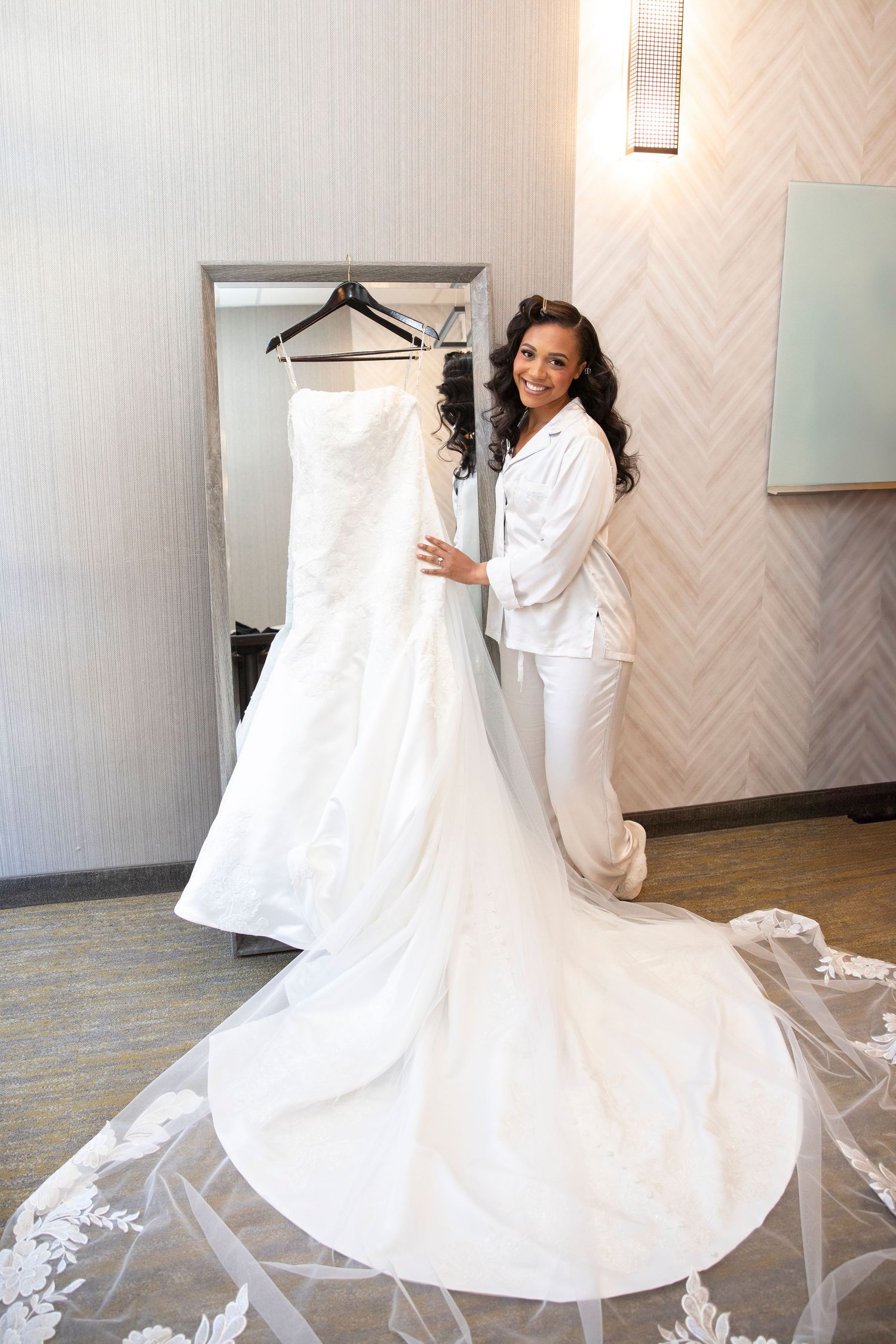 White wedding dress with lace details being prepared in a bridal suite.