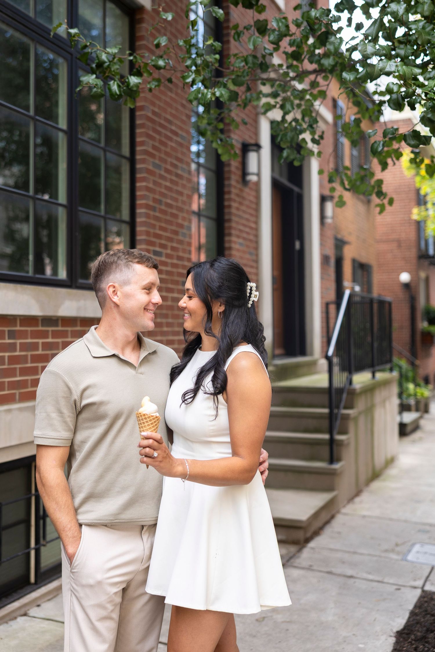 Couple enjoying coffee together outside brick buildings on an urban sidewalk.