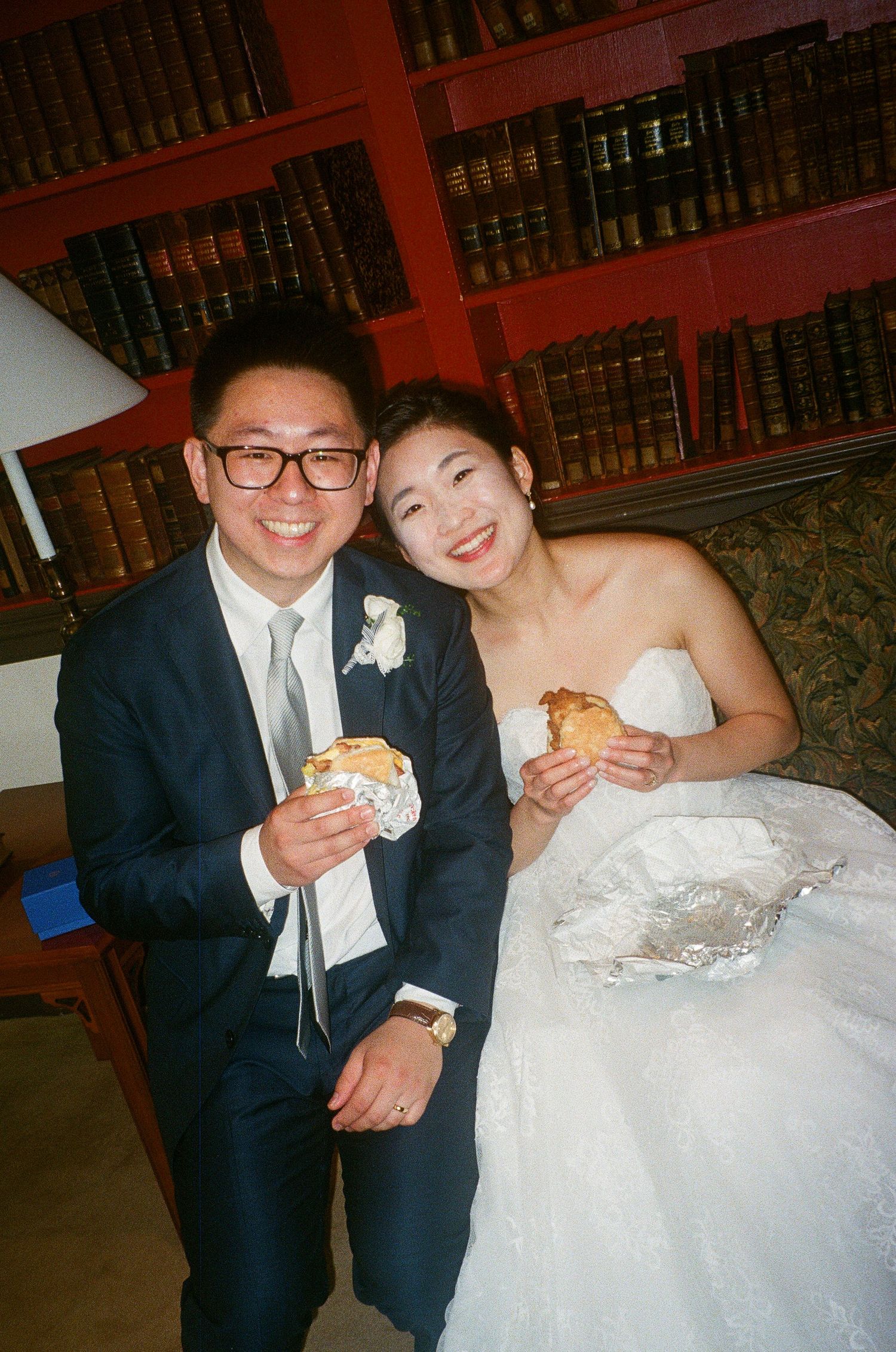 Newlyweds sharing a casual meal together in formal attire at their reception.