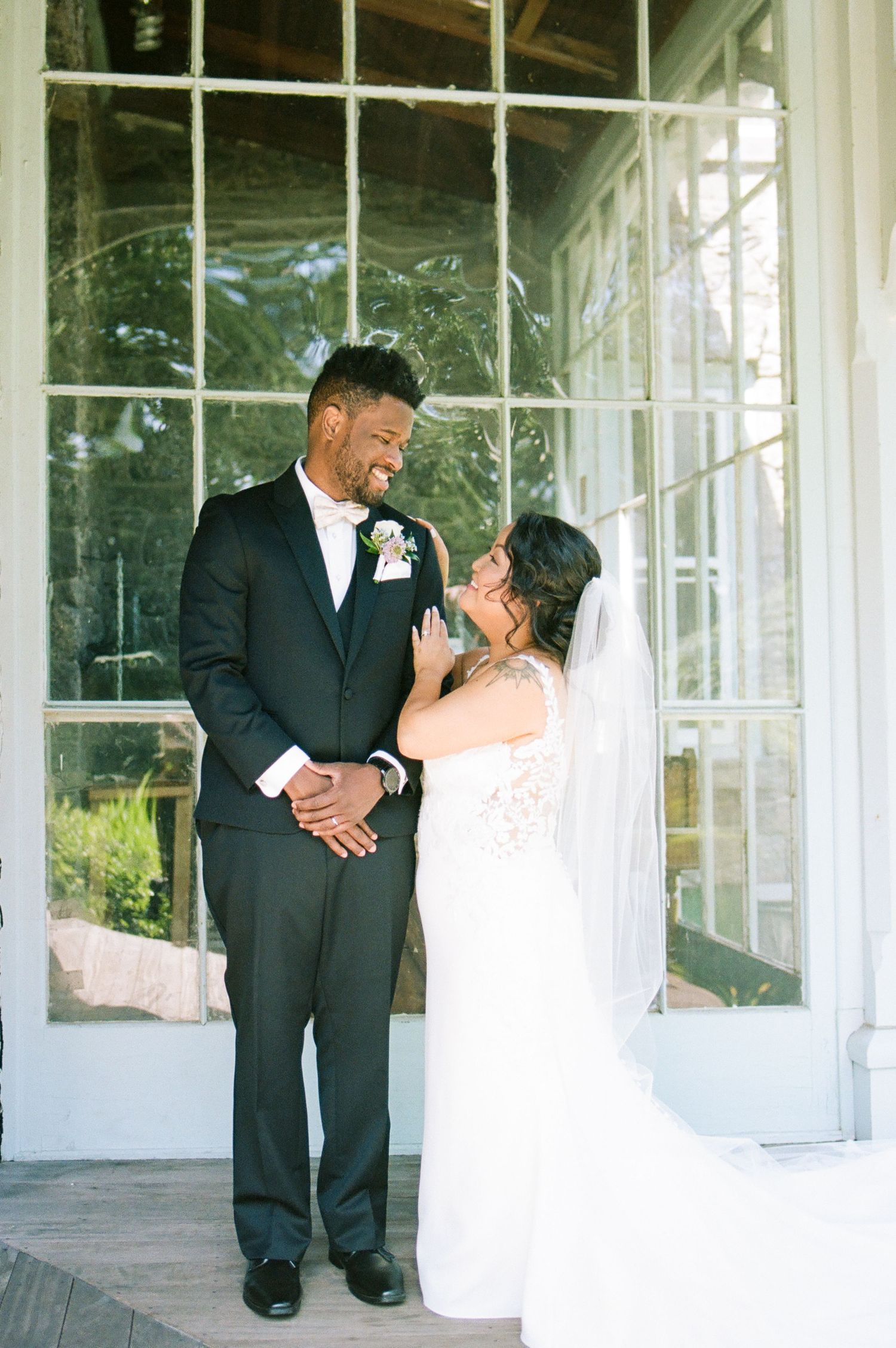 Romantic wedding couple sharing a moment in a sunlit conservatory.