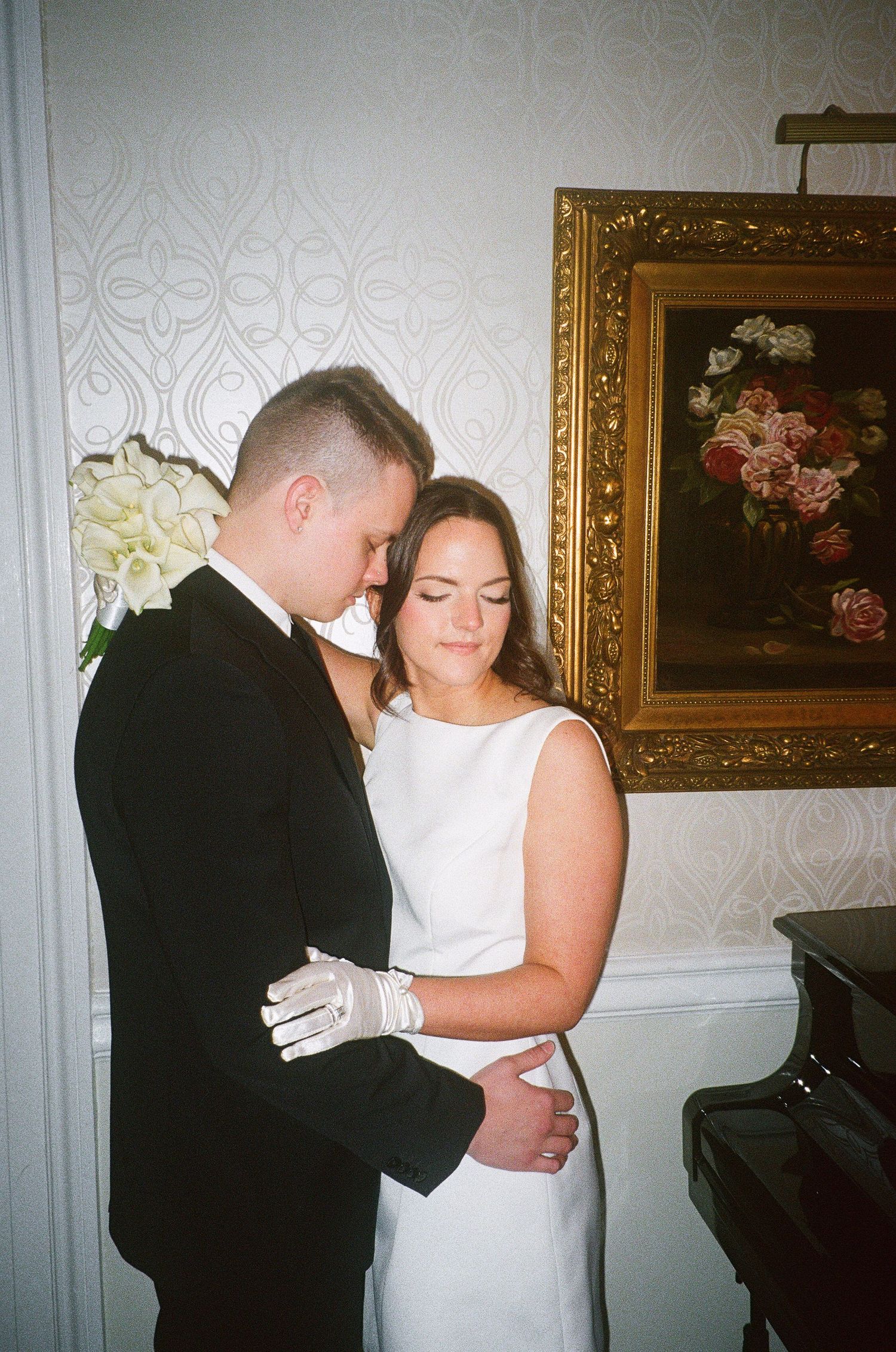 Tender embrace between newlyweds in front of floral wall art.